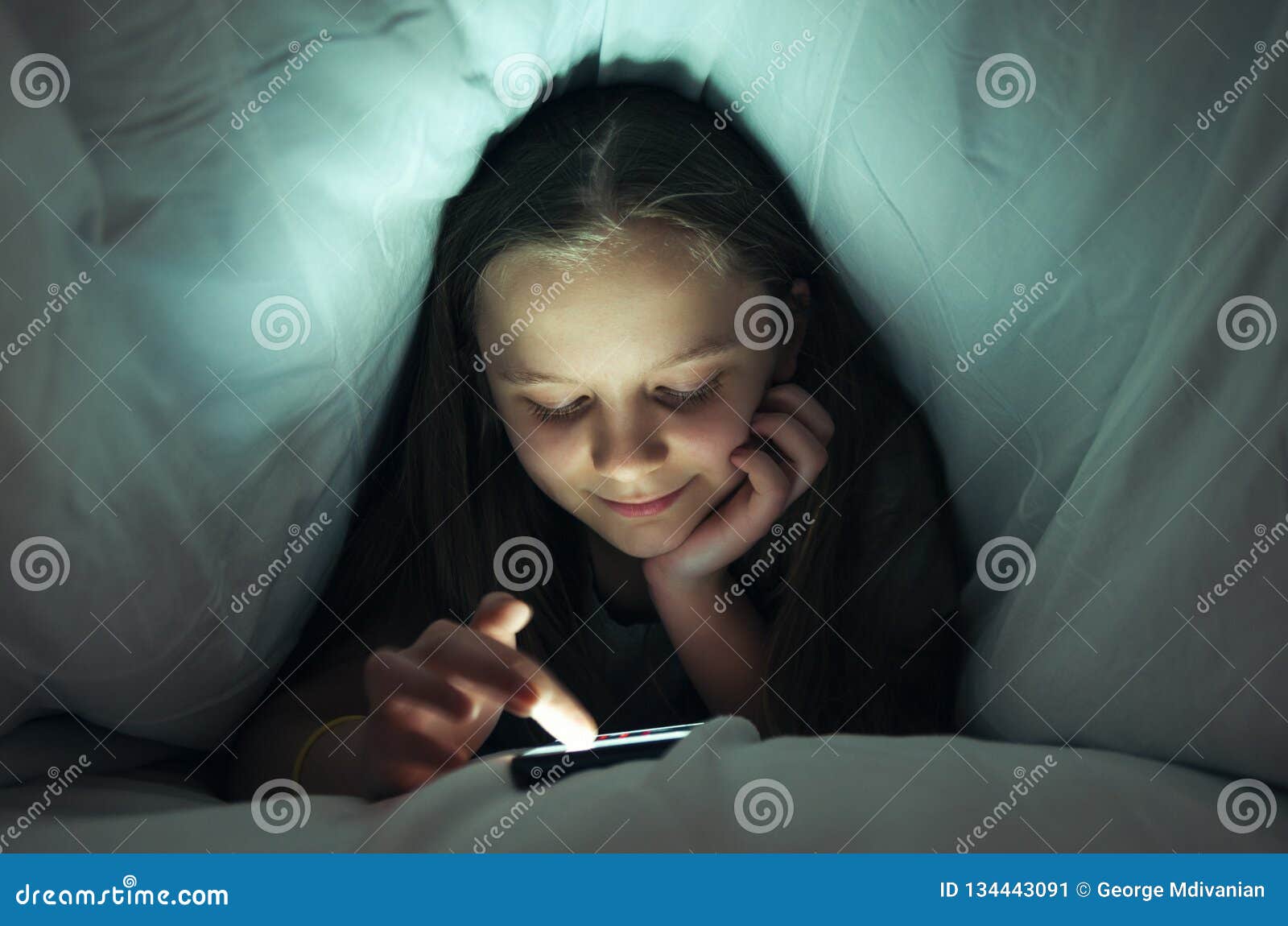 Young girl using a phone in bed