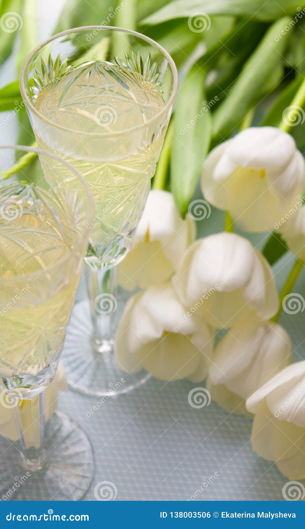 Two glasses with champagne and tulips on a blue background. Two glasses of champagne and tulips on a blue background, festive romantic set