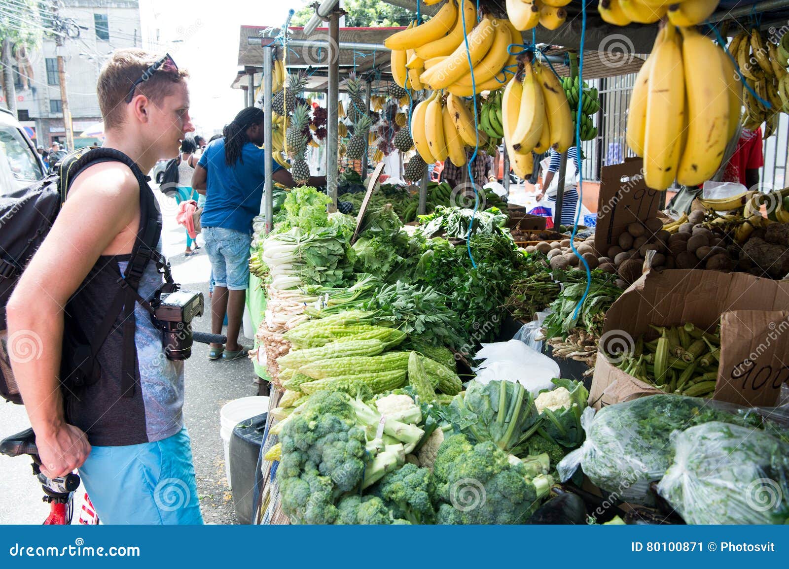 Handsome man buys vegetables. Port of spain, Trinidad and Tobago - November 28, 2015: handsome man caucasian tourist buys vegetables or fruit outdoors on local south market on streetscape background