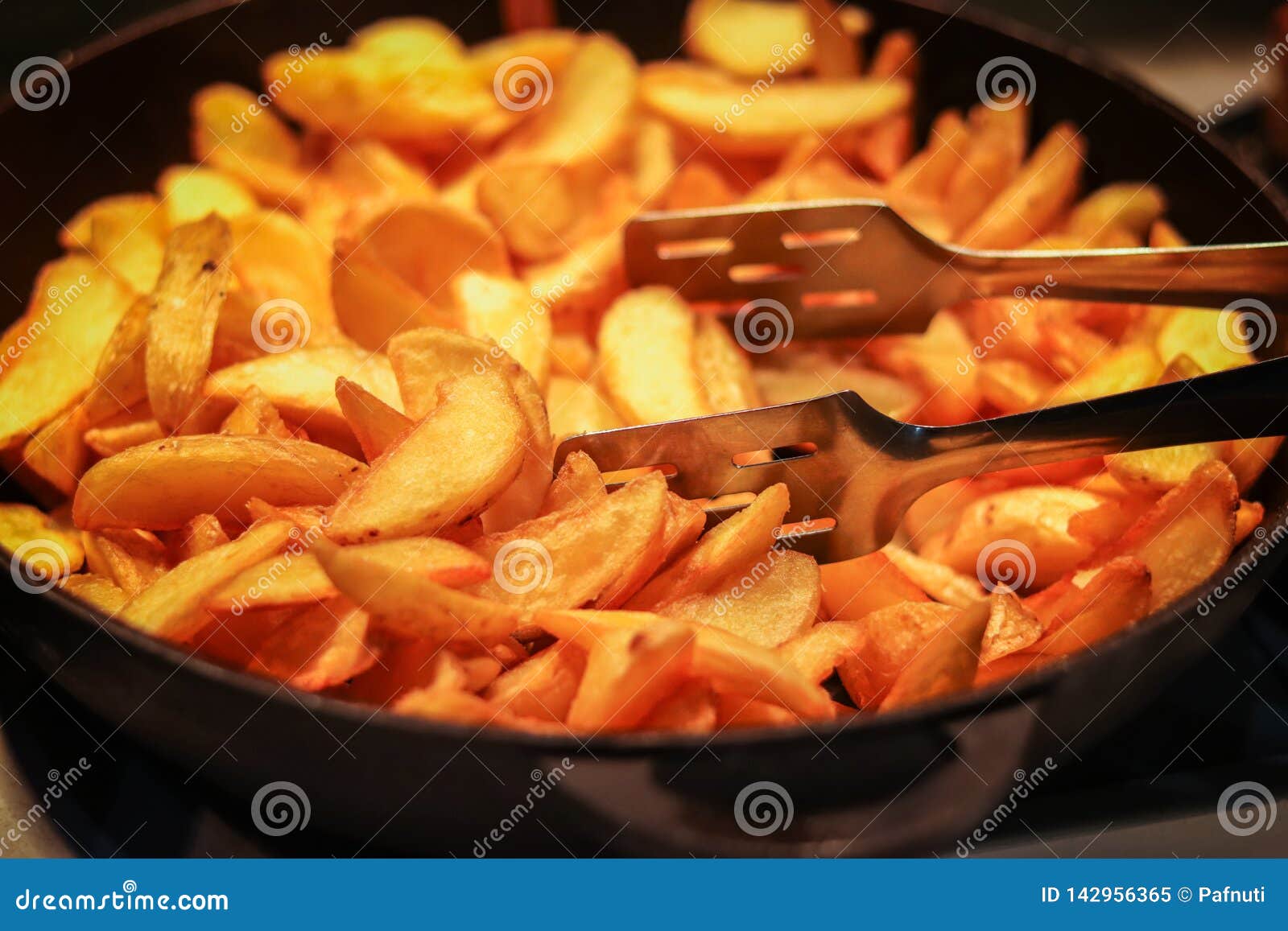 Tasty crispy fried wedges of potato served in an old metal skillet in a close up wide angle view