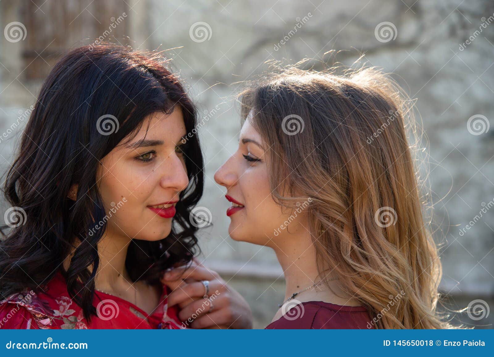 Close up of two female friends, one blonde and the other brunette are smiling cheerfully. Concept of friendship and complicity of Caucasian girls.