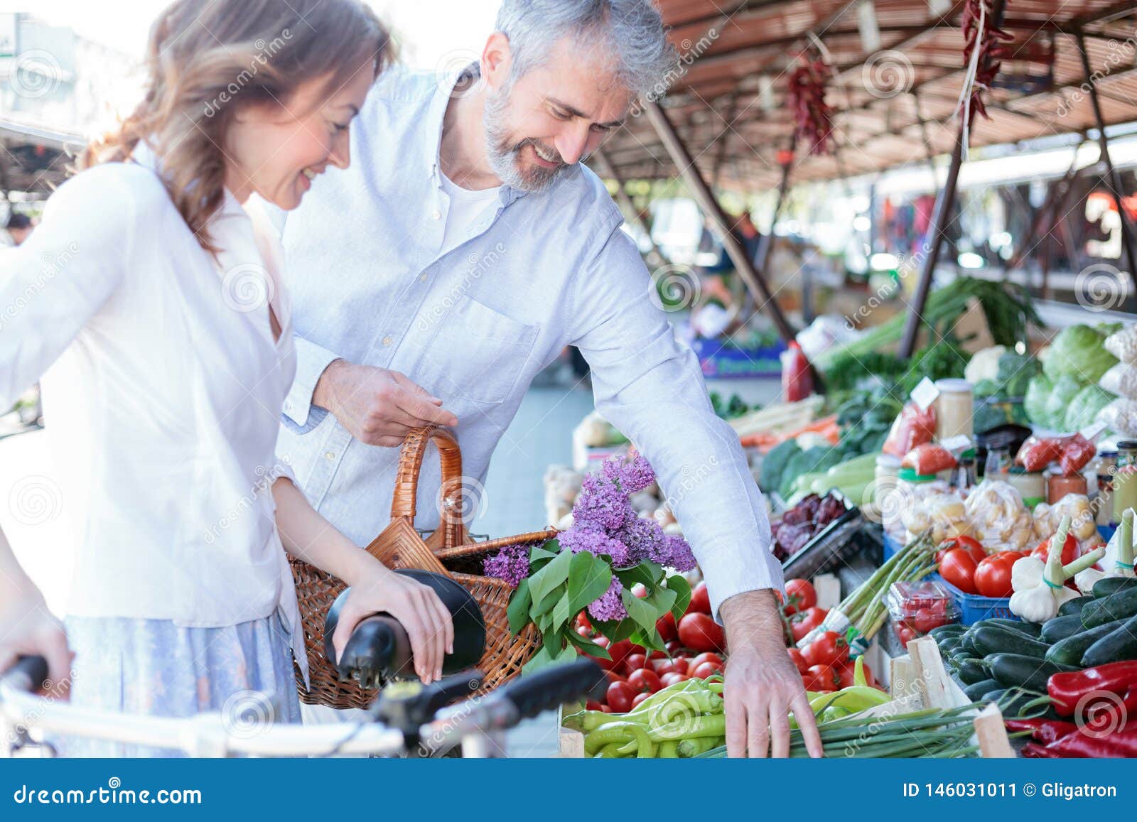 Happy smiling husband and wife shopping for groceries and fresh food in a marketplace. R r