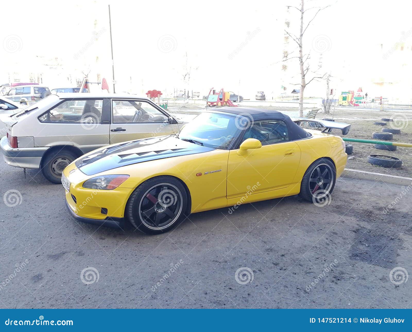 Honda 2000 car, yellow with carbon fiber hood and soft riding in the courtyard of a multistory building, Surgut, Russia - May 13, 2019