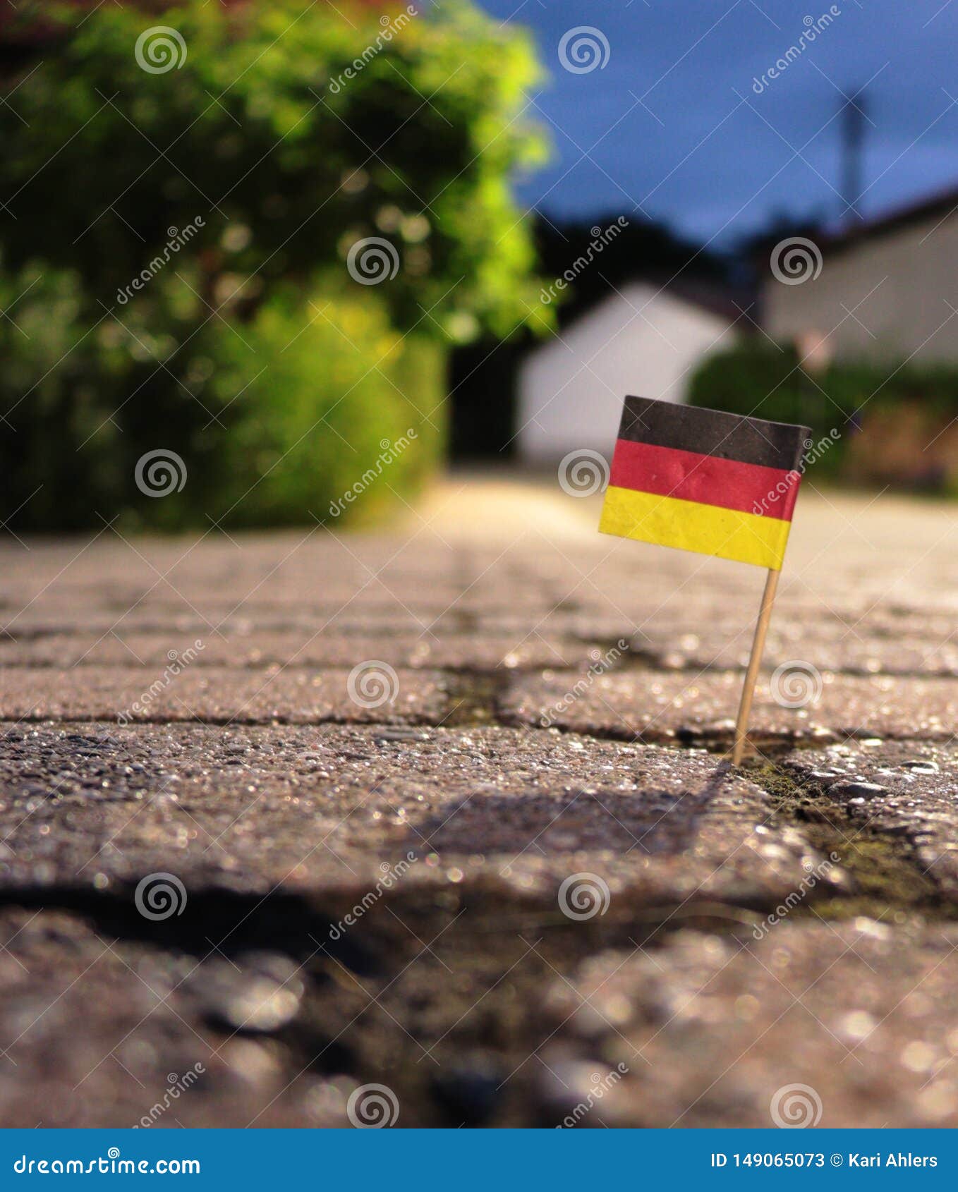 A German toothpick flag is stuck in the sidewalk crack after a night of revelry and celebration