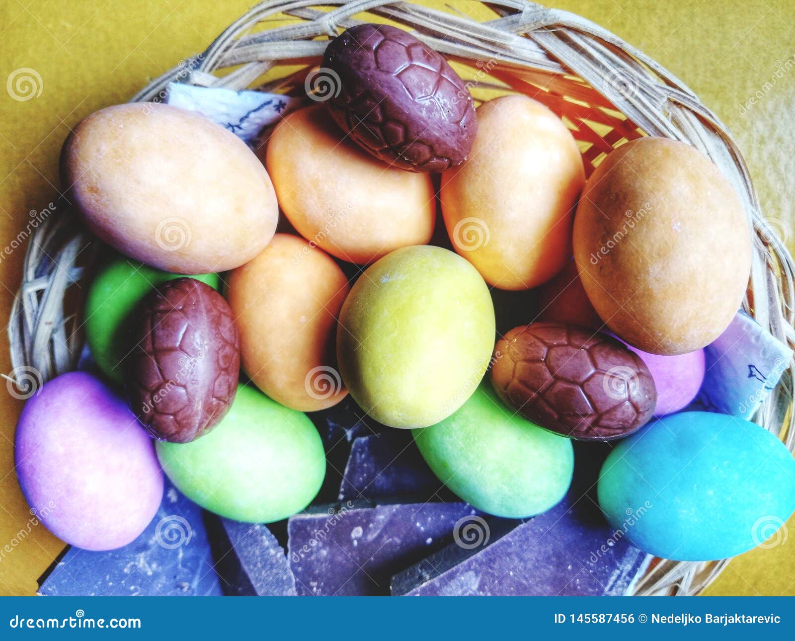 easter basket with colorful eggs and red decorative flowers