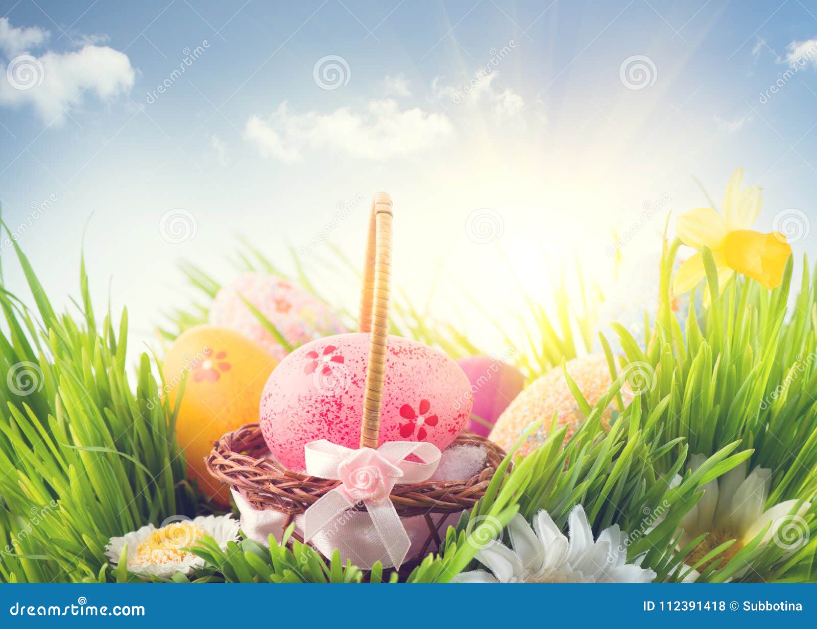 Easter holiday scene background. Traditional painted colorful eggs in spring grass over blue sky. Spring holidays Easter backdrop