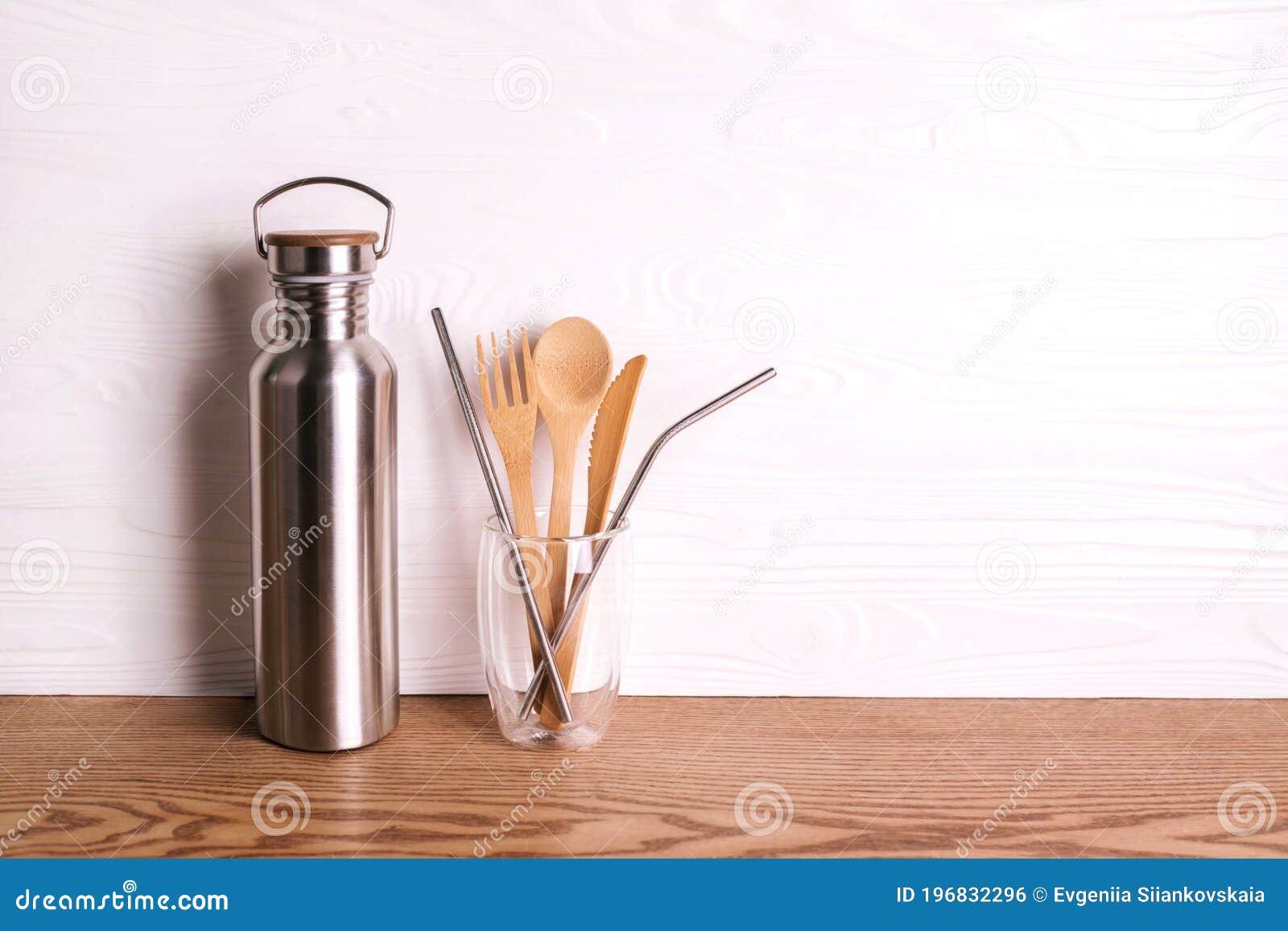 eco set with bamboo cutlery, reusable water bottle on wooden background.