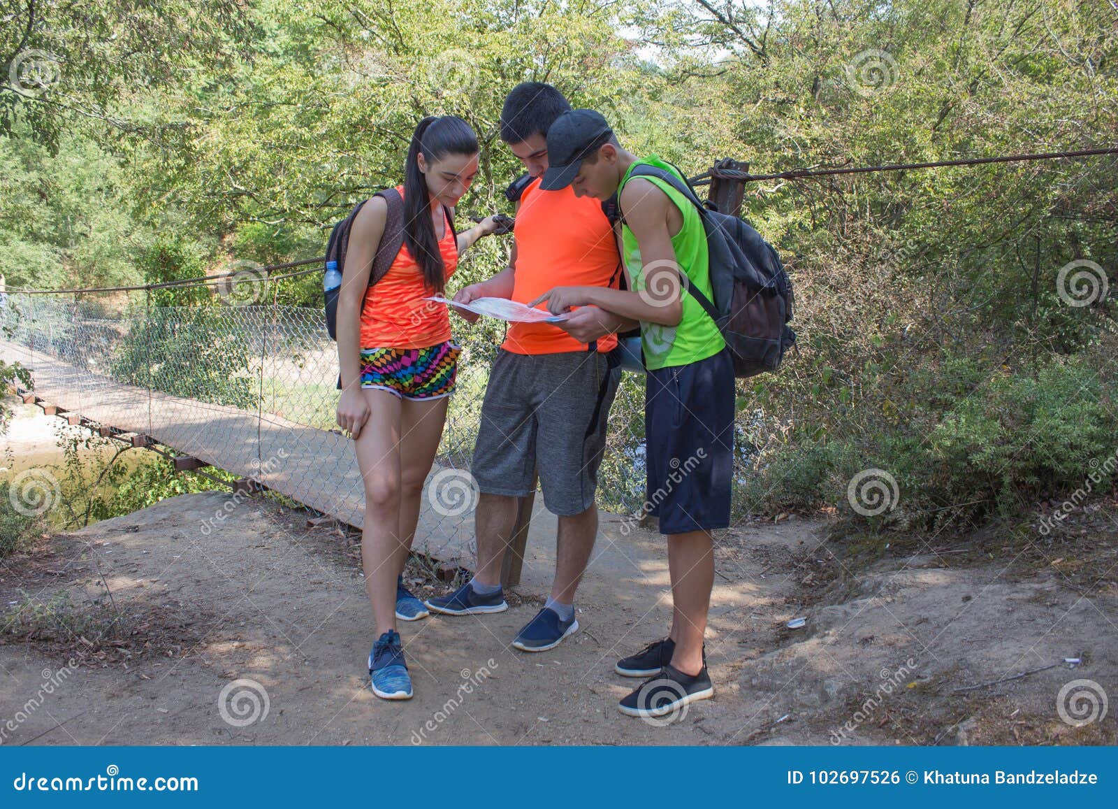 eco tourism and healthy lifestyle concept. young hiker girl end boys with backpack. travelers, hikers on vacation reading a map