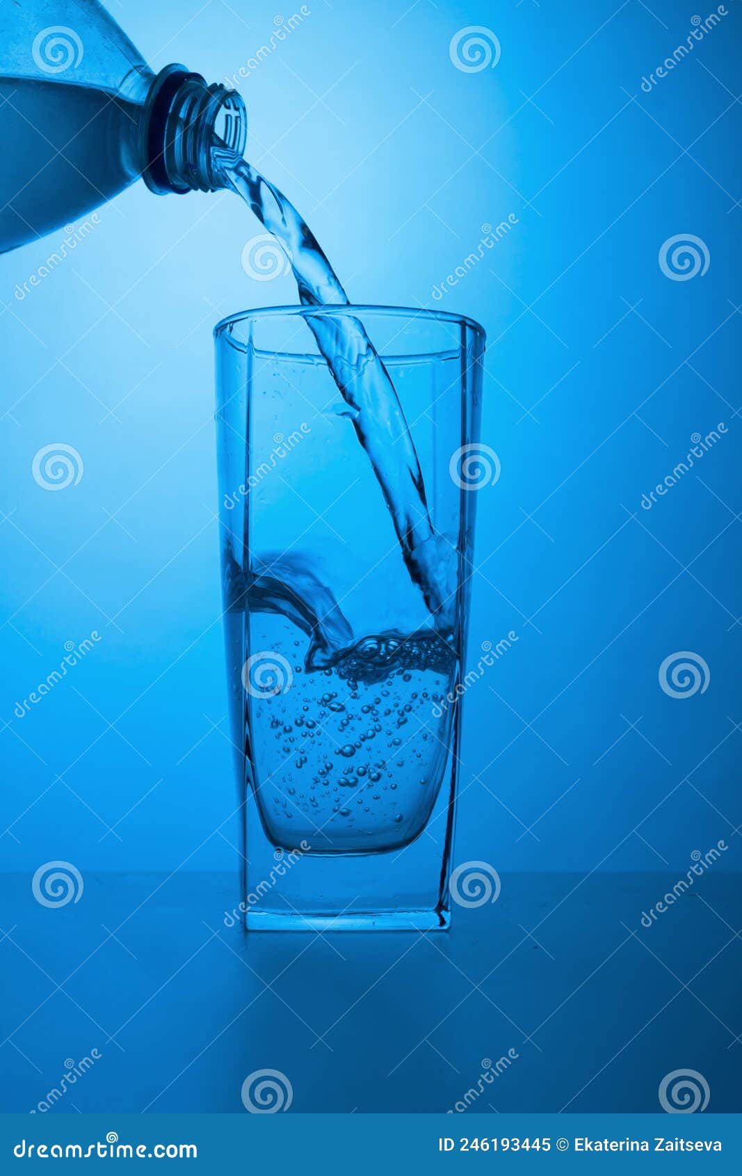 Ecologically Clean Water is Poured from a Bottle into a Glass on a Blue
