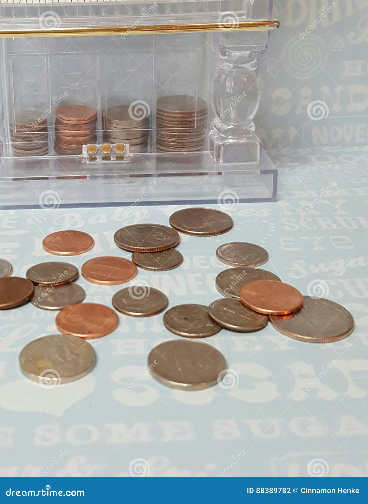 Economia para um deleite doce. O banco de moeda de classificação e de empilhamento antiquado com as moedas de um centavo, os níqueis, as moedas de dez centavos e os quartos mostrados interno e algumas moedas dispersou na frente dele