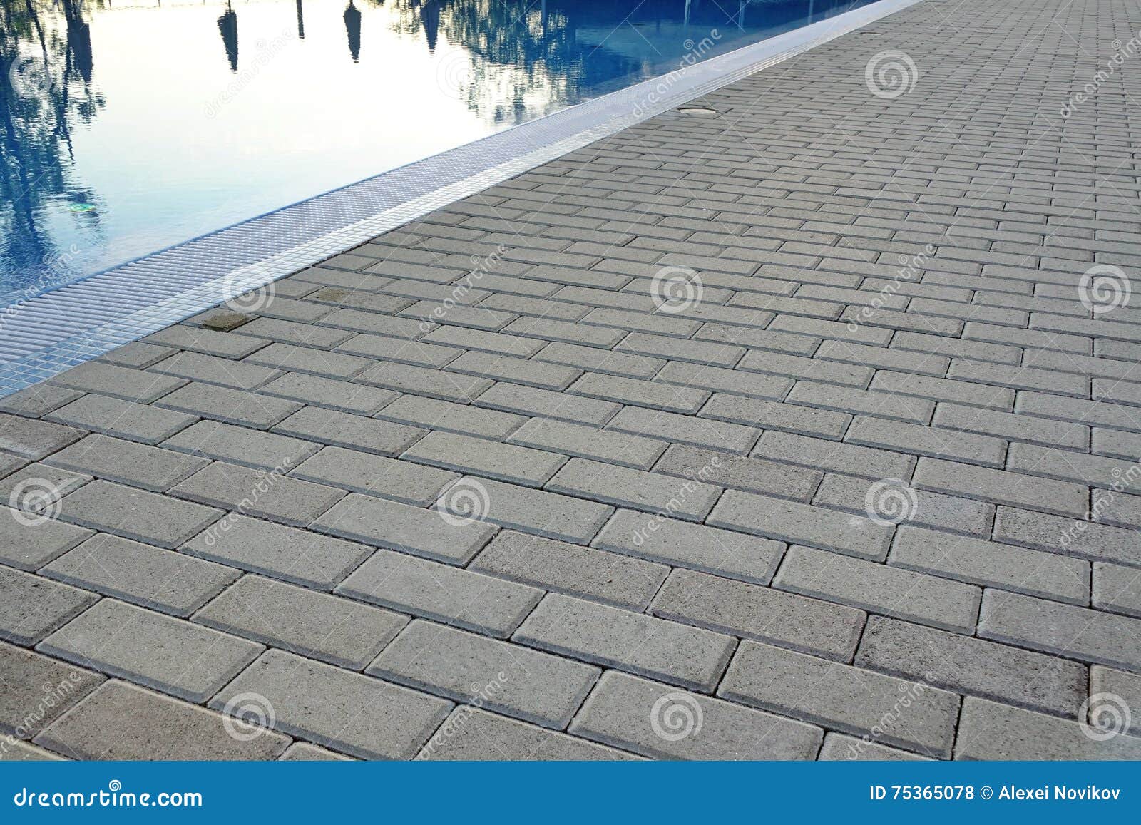 edge of swimming pool with reflection and concrete paving