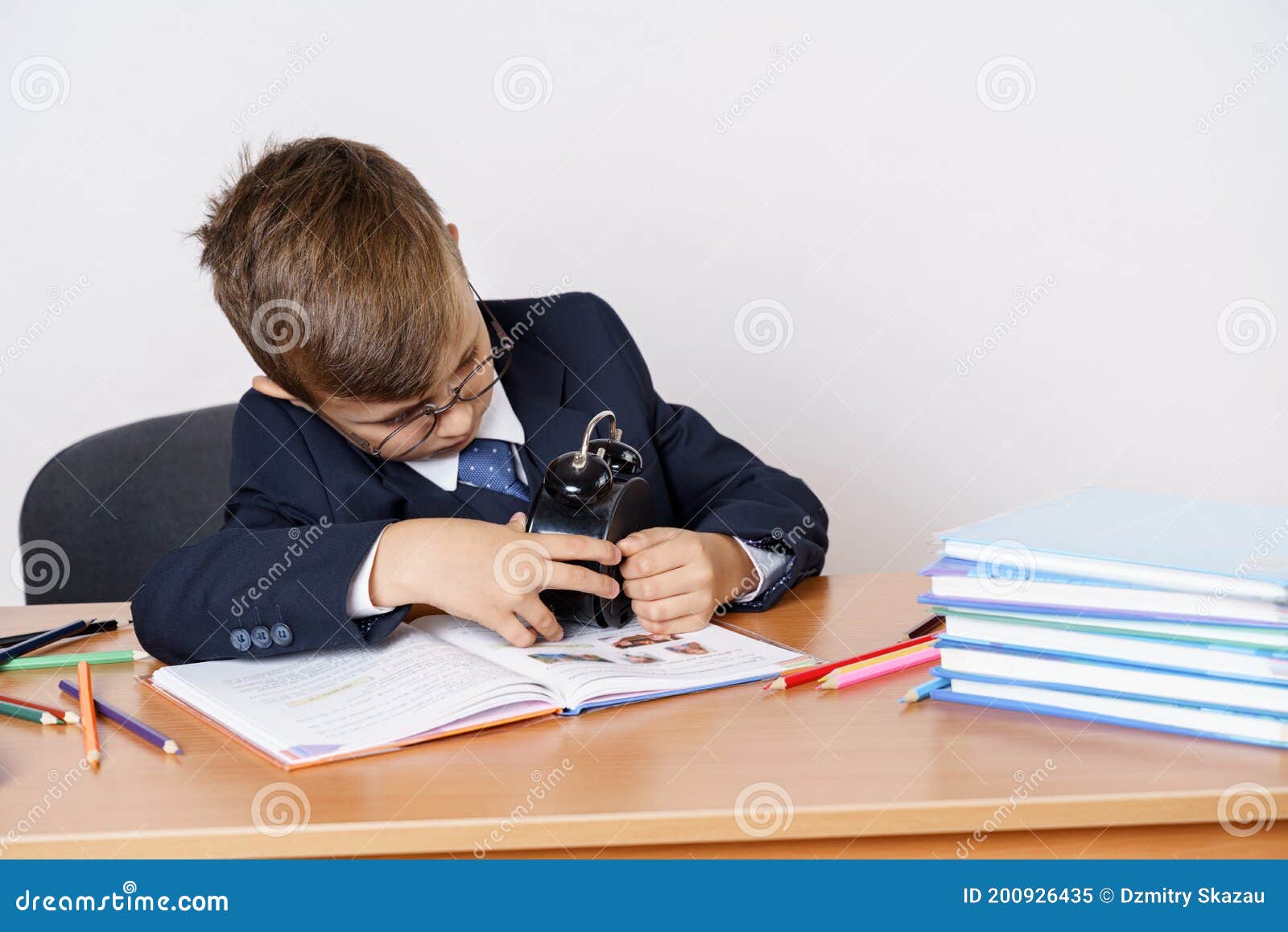 The Student Sits at the Table, Does His Homework and Looks at the Clock