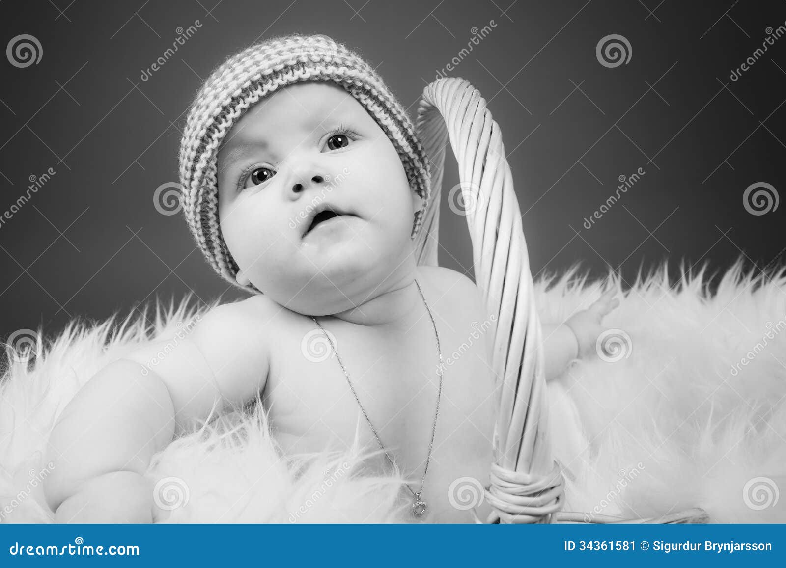 Een babymeisje in een mand. Een zitting van het babymeisje in een mand voerde met bont.