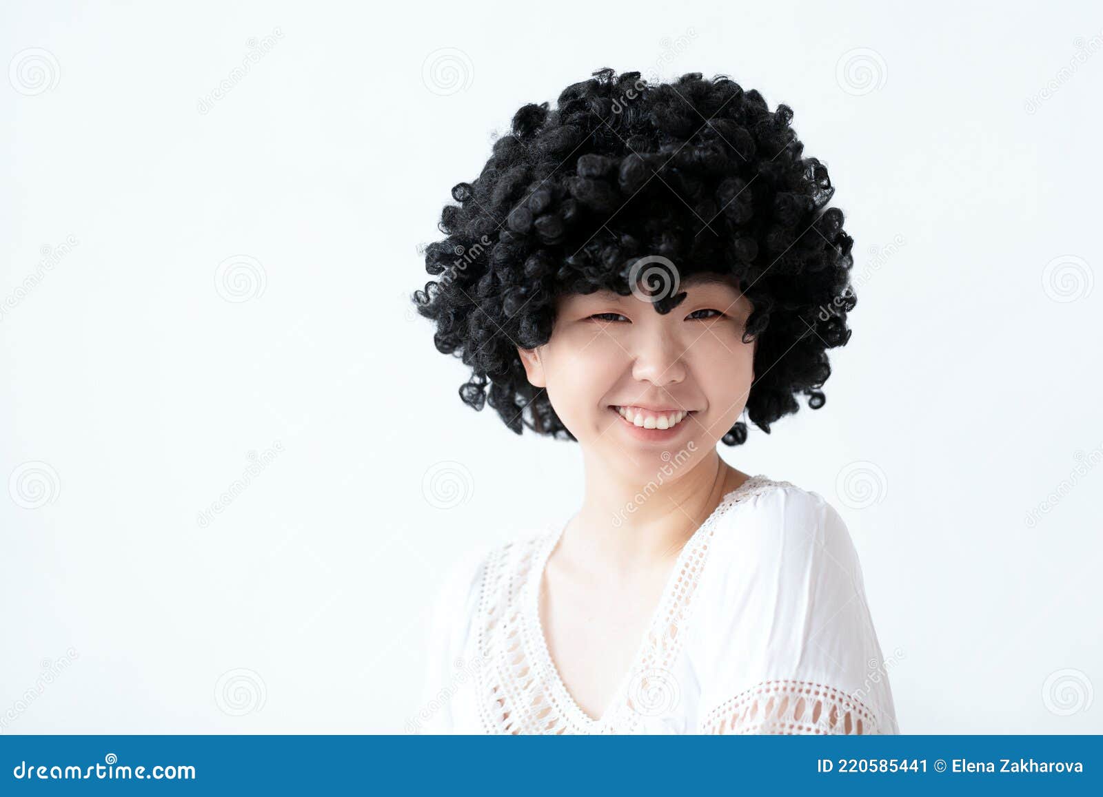 Een Grappige Aziatische Vrouw Met Een Glimlach Op Een Afro Pruik Op Een Achtergrond in De Studio. Stock Afbeelding - Image of gezicht, dame: