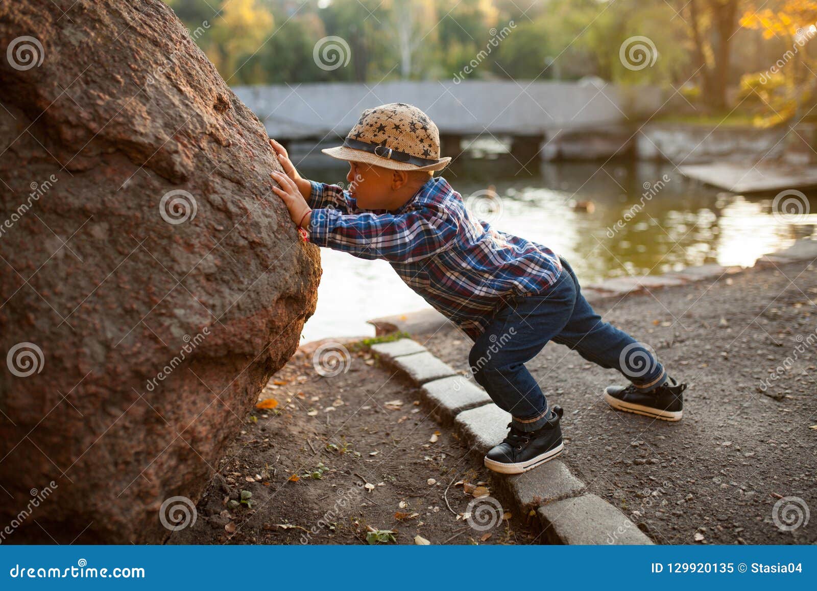 Een Kleine Jongen Speelt En Duwt Een Rots Tijdens Een Gang In Stock Afbeelding - Image Of Kust, Ontspan: 129920135