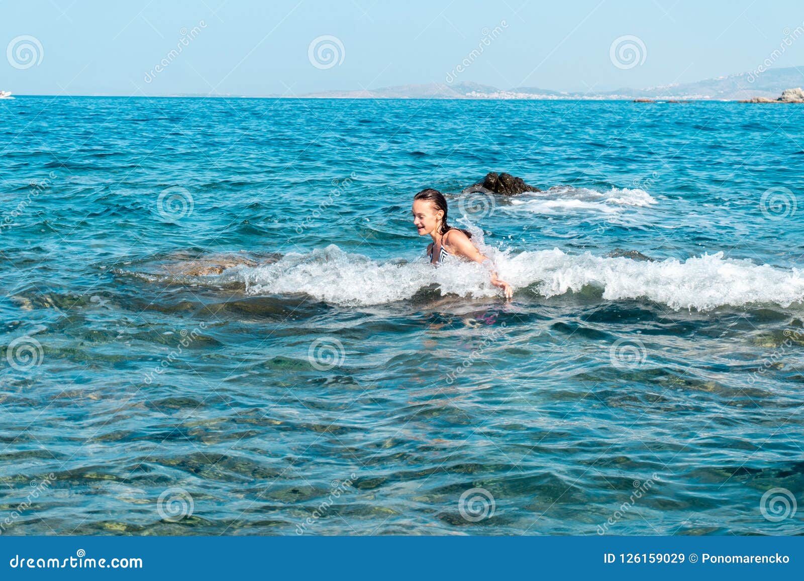 Een vrolijk jong meisje zwemt in het overzees. Een vrolijk meisje in overzeese plavae