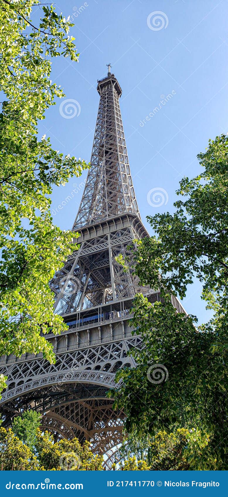 effel tower in paris against a bright blue sky and green trees