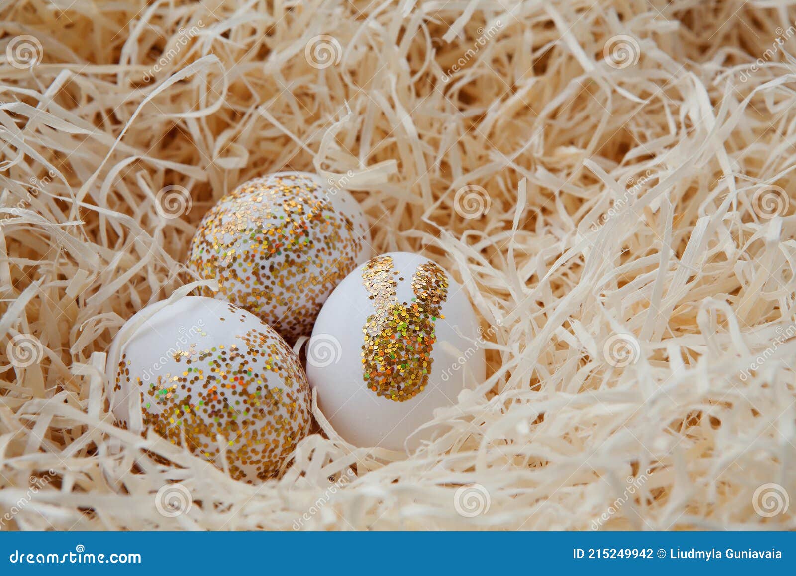 Eggs Decorated with Gold Glitter Bunny on Straw Background. Easter