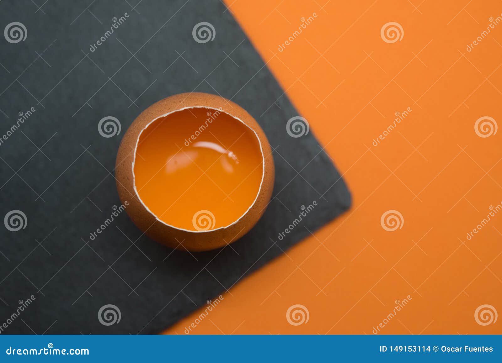 open egg with the yolk on the orange background.