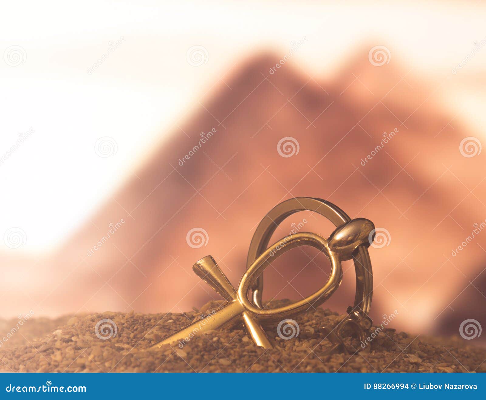 Egyptian Cross Ankh. The Egyptian ankh is a cross in the sand against the backdrop of the Great Pyramids. Photo toned.