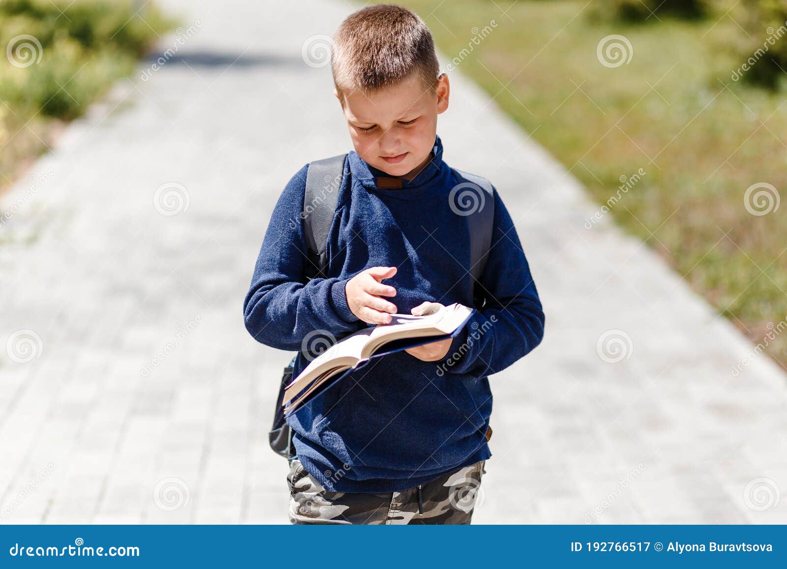 Eightyearold Boy with a Book in His Hand and a Backpack on His Back