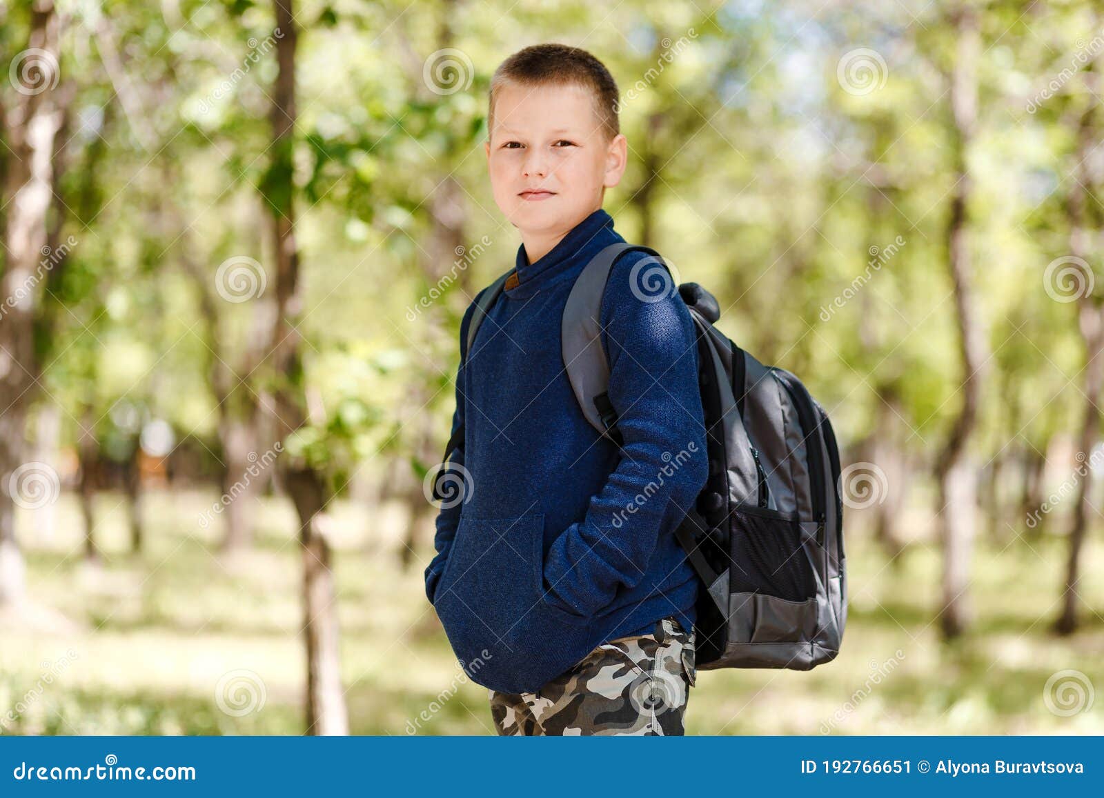 Eightyearold Shorthaired Boy in a Blue Sweater with a Backpack on