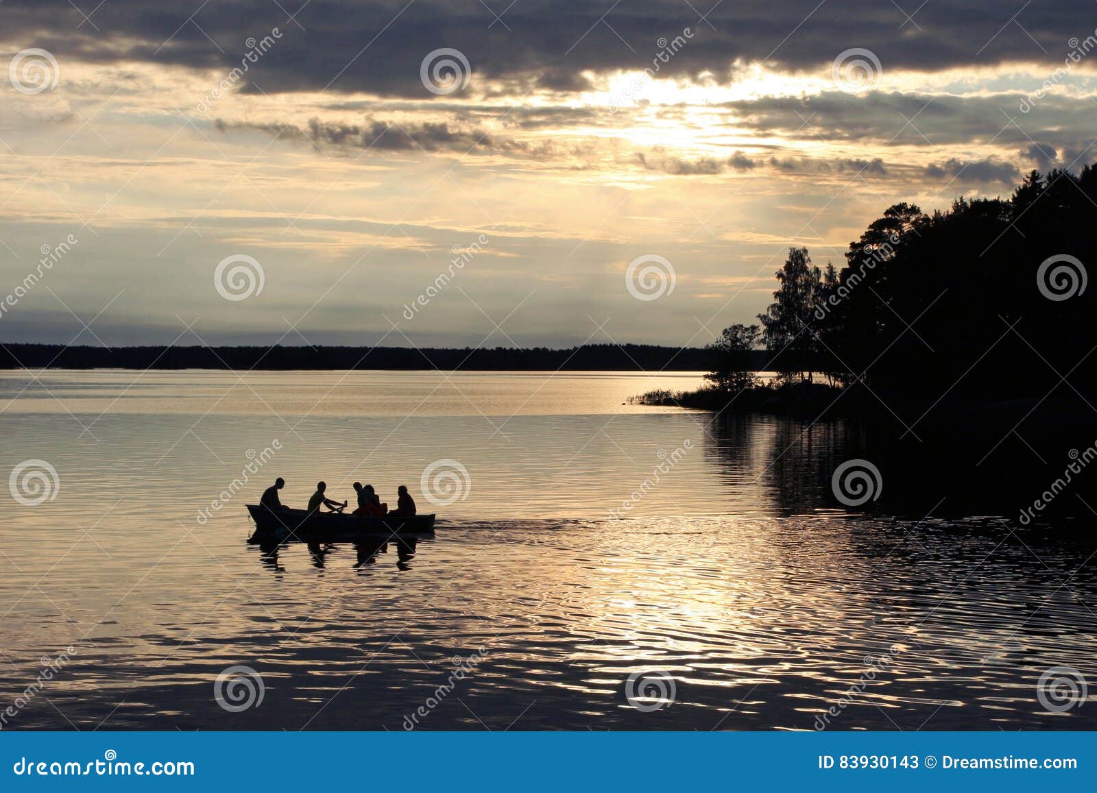 Ein Boot auf einem See. Gruppe von Personen in einem Boot auf einem See während des Sonnenuntergangs