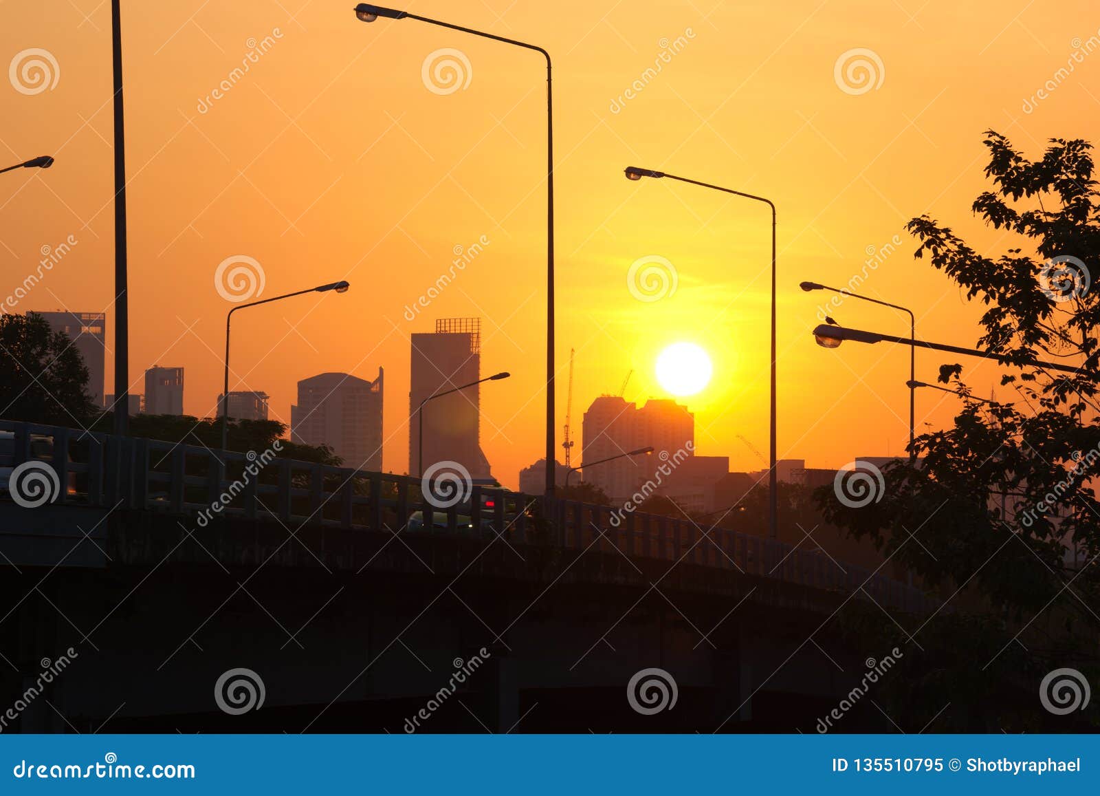 Ein bunter Sonnenaufgang von orange und gelben Farben, über dem dunklen Schattenbild einer Brücke in Bangkok, Thailand. Ein unerwarteter, majestätischer, bunter Sonnenaufgang von orange und gelben Farben, über dem Schattenbild einer Brücke mit hellen Pfosten, in einem weckenden â€œCity von Angelsâ€-; Bangkok, Thailand