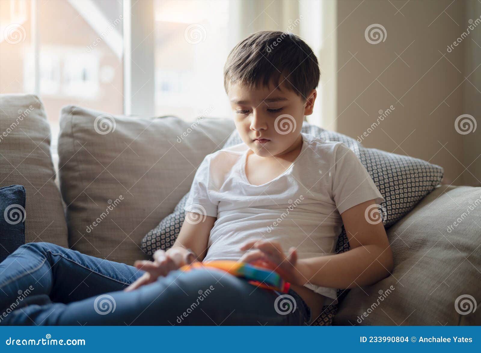Ein Glückliches Kind, Das Auf Einem Sofa Sitzt Und Einen Bunten  Plastikspieß Spielt. Hallenportrait Mit Einem Süßen Kind Entspanne Stockfoto  - Bild von hintergrund, ausbildung: 233990804