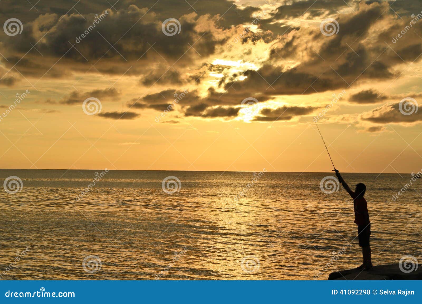 Ein Mannfischen während des Sonnenuntergangs. Ein Schattenbild eines Mannfischens mit einem schönen, goldenen Sonnenuntergang und einem orange Himmel als Hintergrund