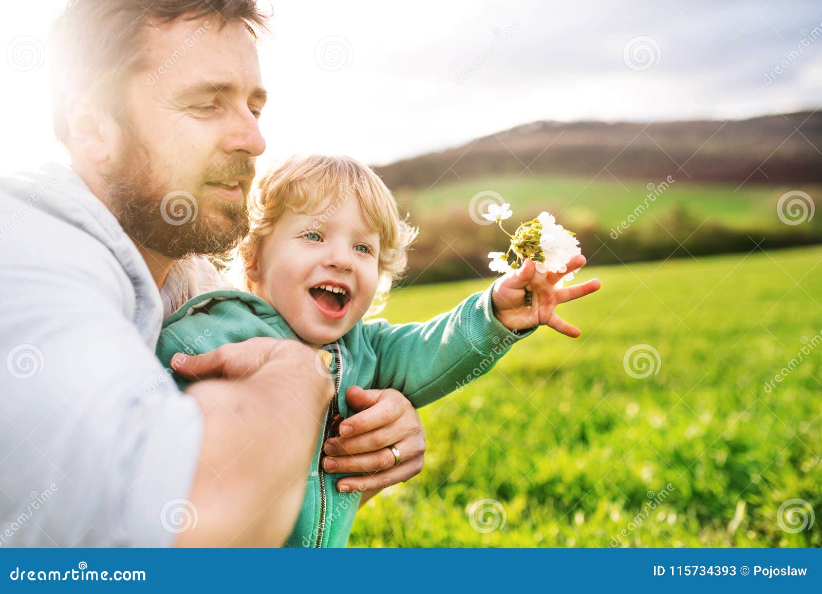 Ein Vater mit seiner Natur der Kleinkindsohn-Außenseite im Frühjahr. Ein Vater mit seinem Kleinkindsohn draußen in der grünen sonnigen Frühlingsnatur