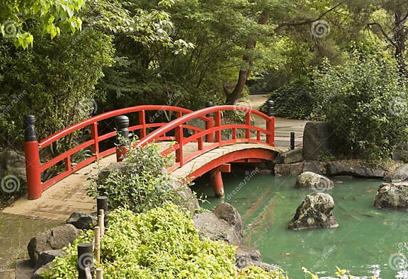 Eine Rote Hölzerne Brücke über Einem Teich in Einem Japanischen Gard