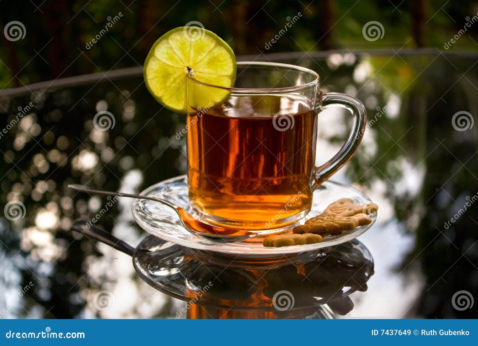 Eine Tasse Tee mit Zitrone und Biskuiten auf einer Glastabelle