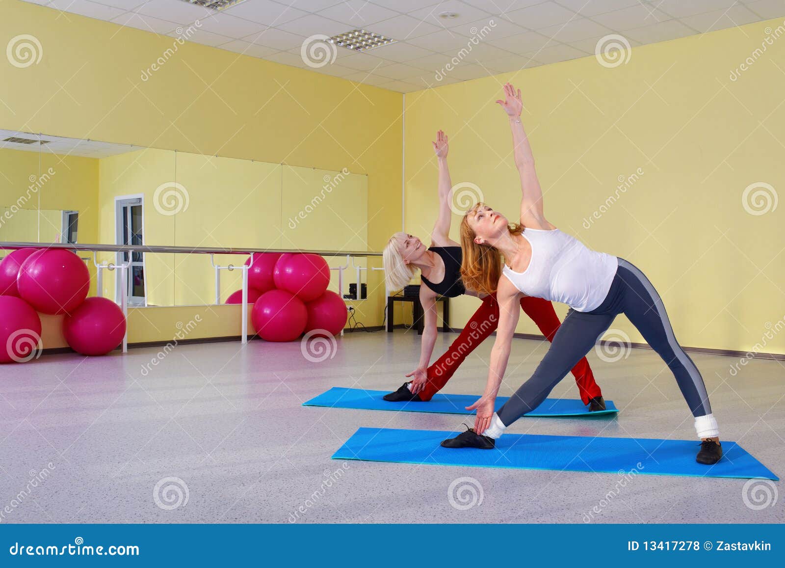 Ejercicio de las mujeres. Retrato de interior del grupo de las mujeres en gimnasia que ejercitan en las alfombras