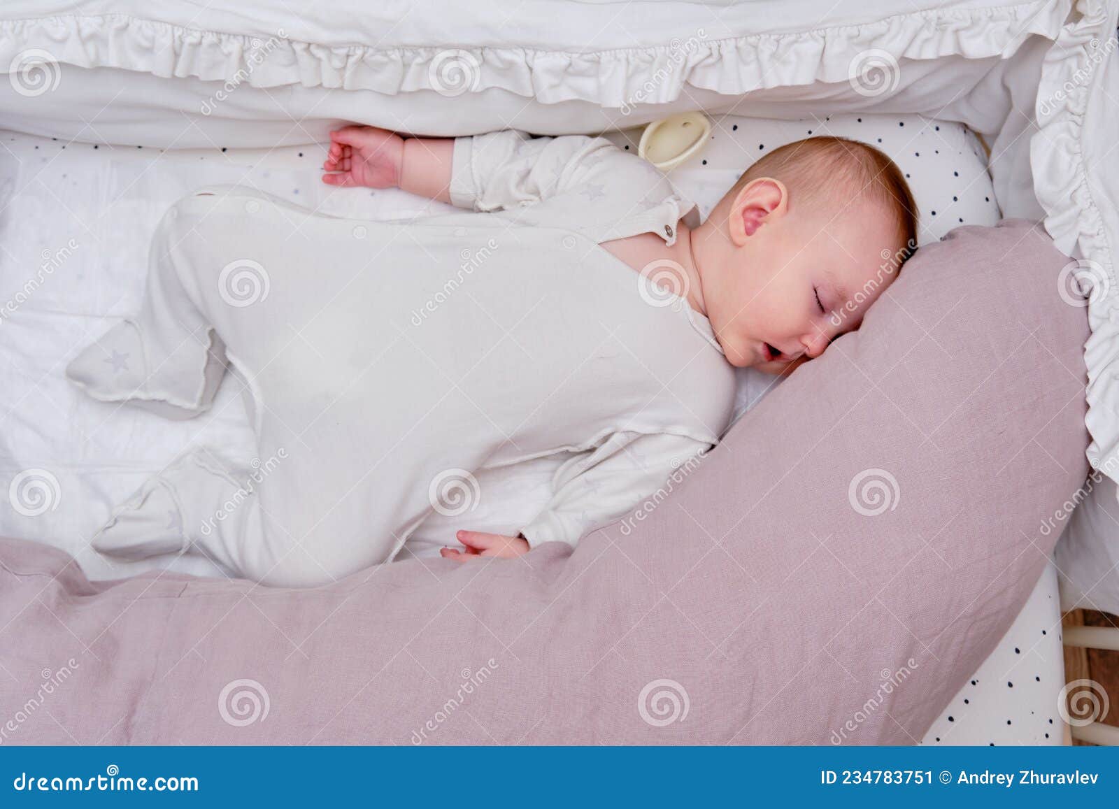 El Bebé Duerme En La Cama Junto a Una Almohada Grande. Niño Se