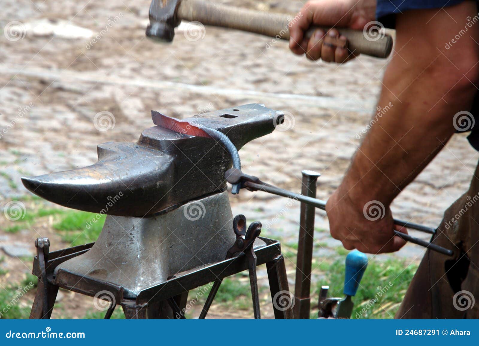 Herrero forja una herradura en el yunque con una herramienta resistente,  close-up