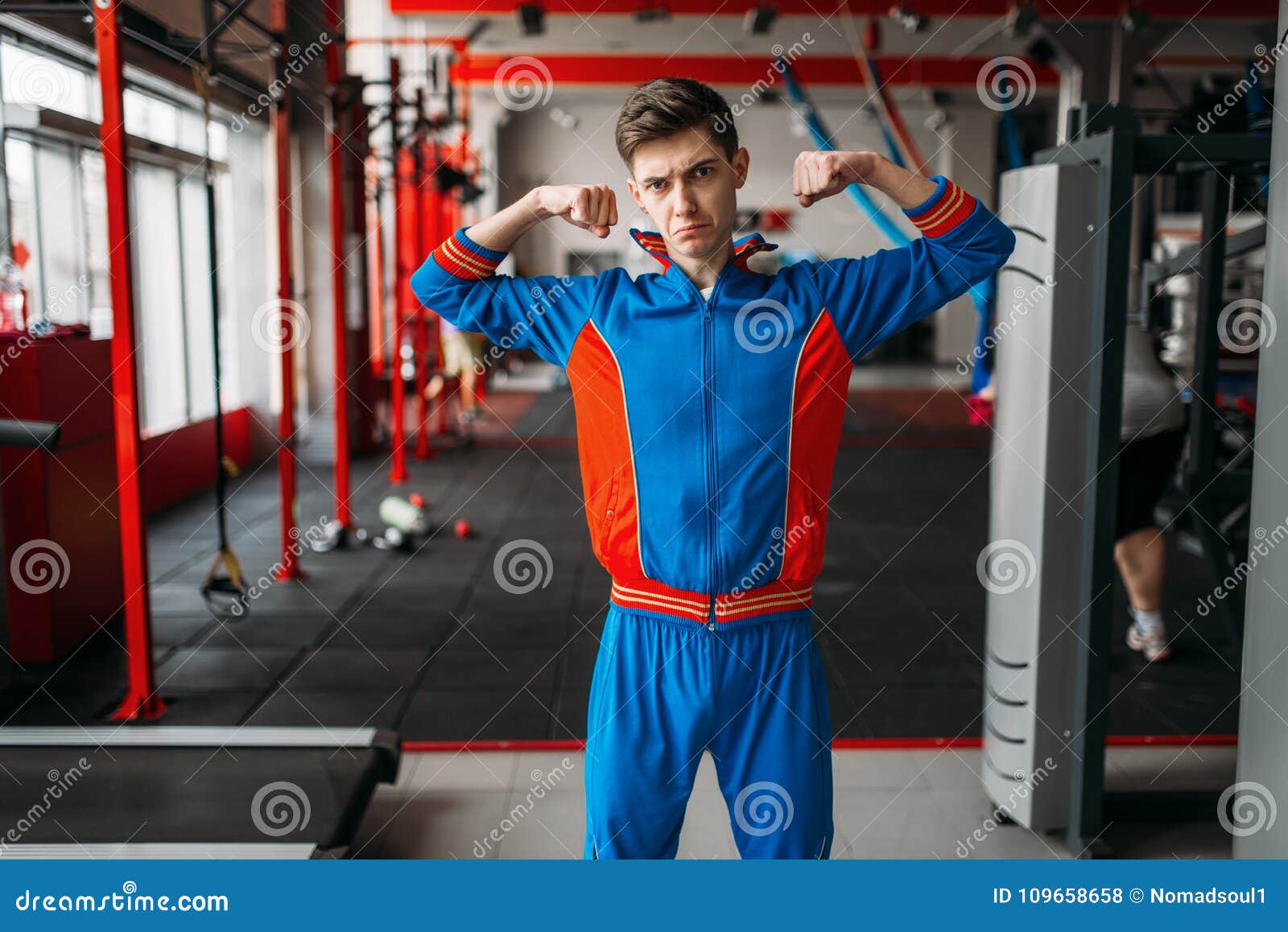 El Hombre Flaco En Ropa De Deportes Muestra Sus Músculos, Gimnasio