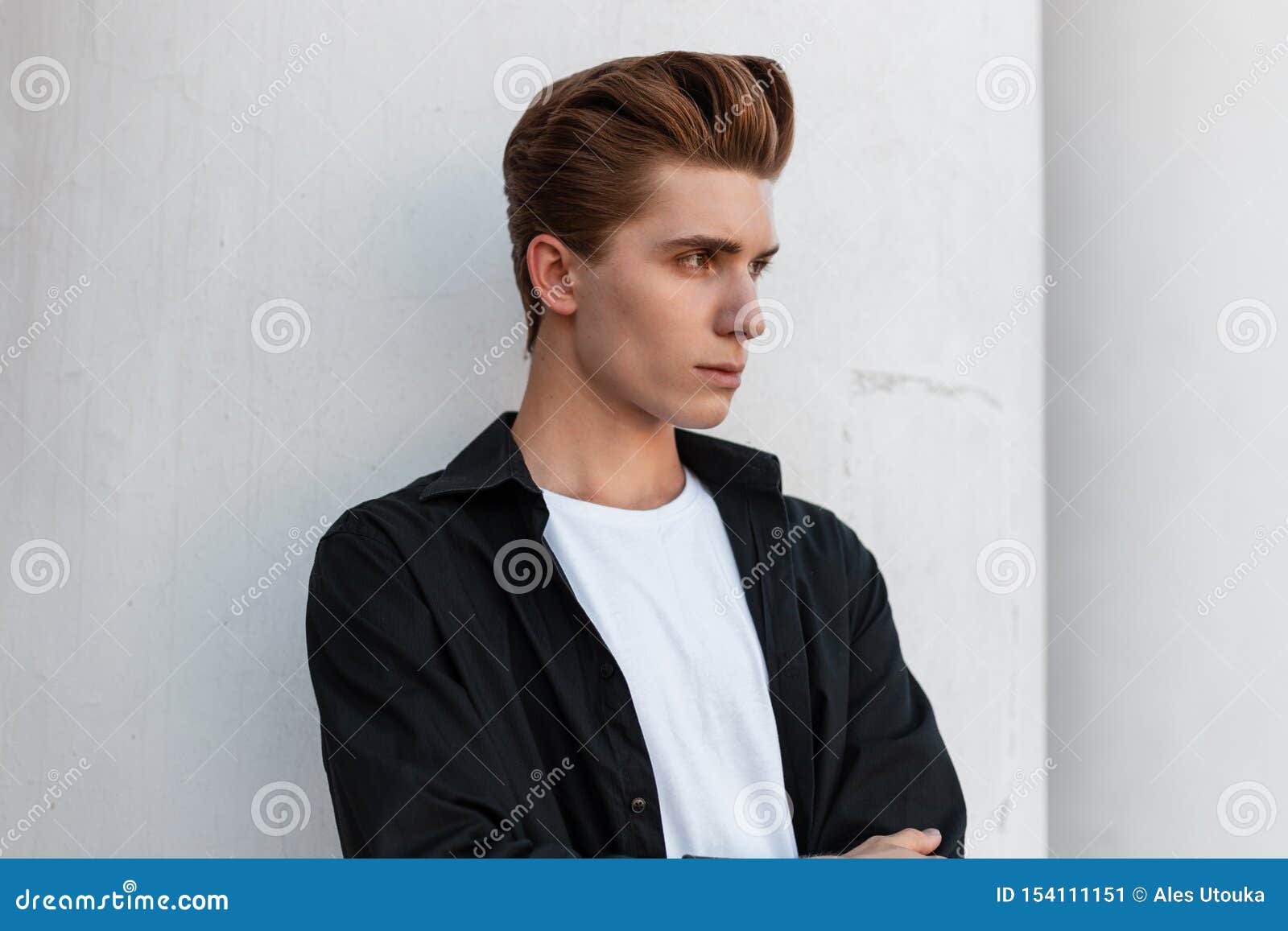 El Hombre Joven Urbano Con Un Peinado Elegante En Una Camisa Negra Elegante  En Una Camiseta Blanca Se Está Colocando Cerca De Un Imagen de archivo -  Imagen de atractivo, lindo: 154111151