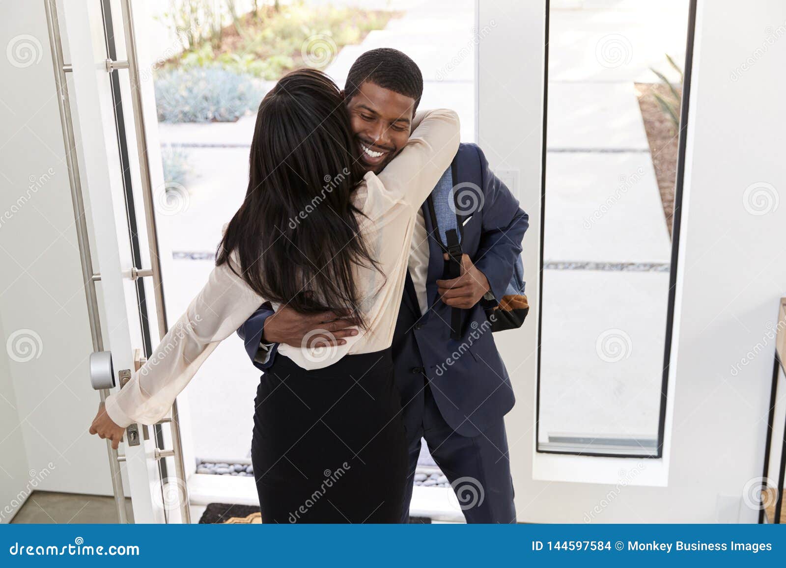 El Saludo De La Mujer Y El Hombre De Negocios Husband As He Del Abrazo Vuelve A Casa De Trabajo