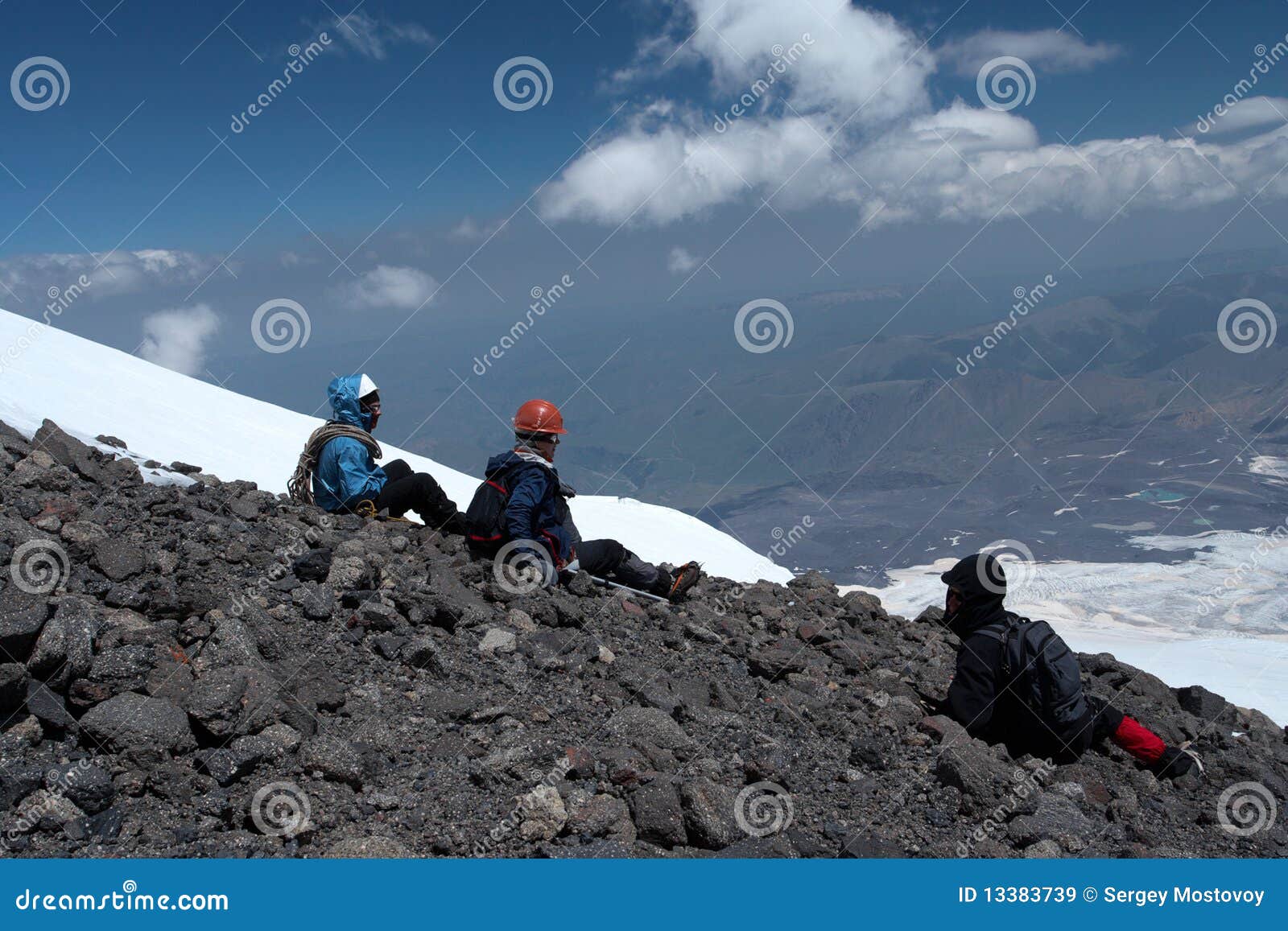 El sentarse en una tapa. Escaladores que se sientan en una cumbre de la montaña y que miran la gran visión panorámica