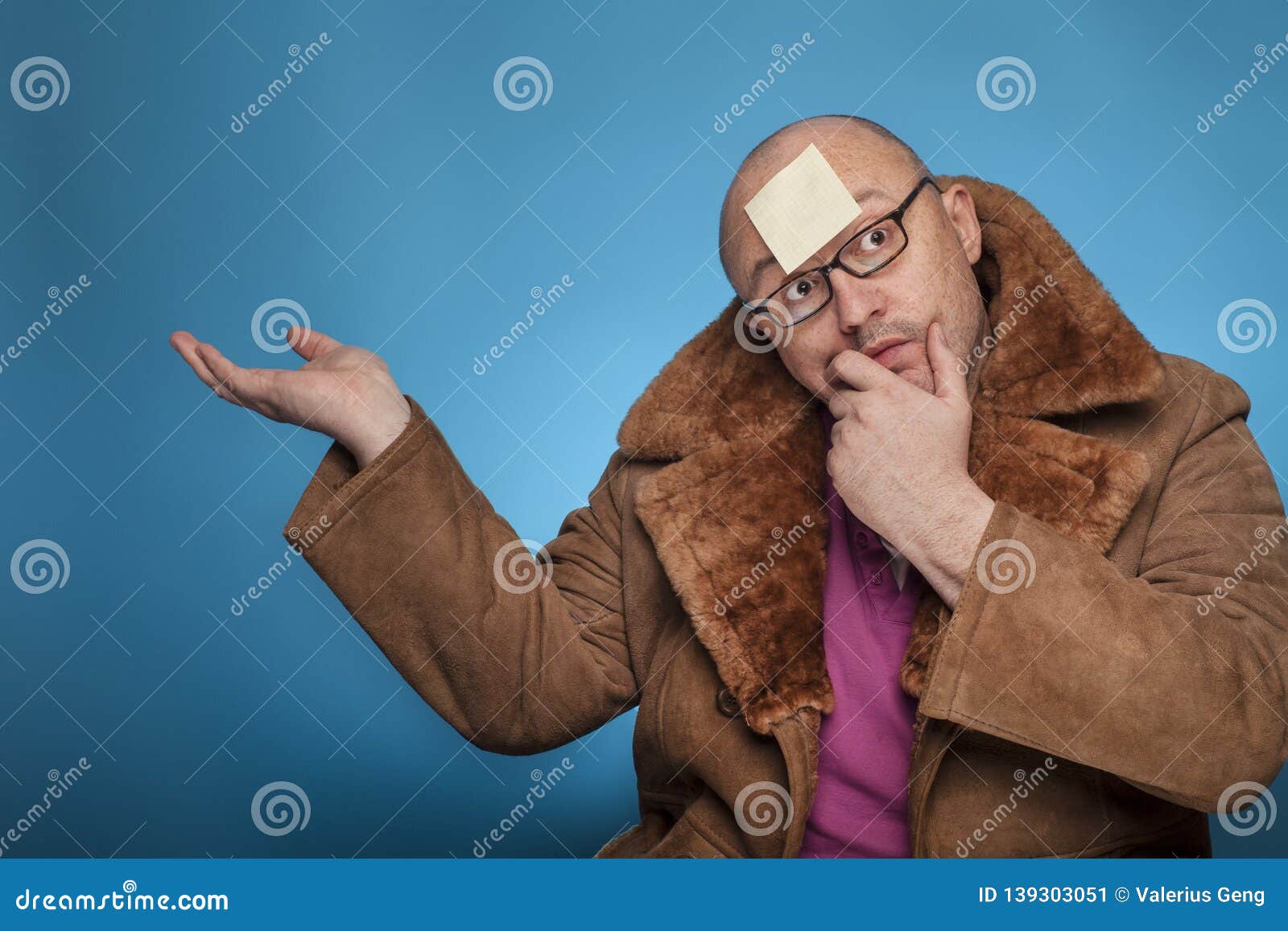 an elderly bald man in a fur coat has a blank post it on the forehead