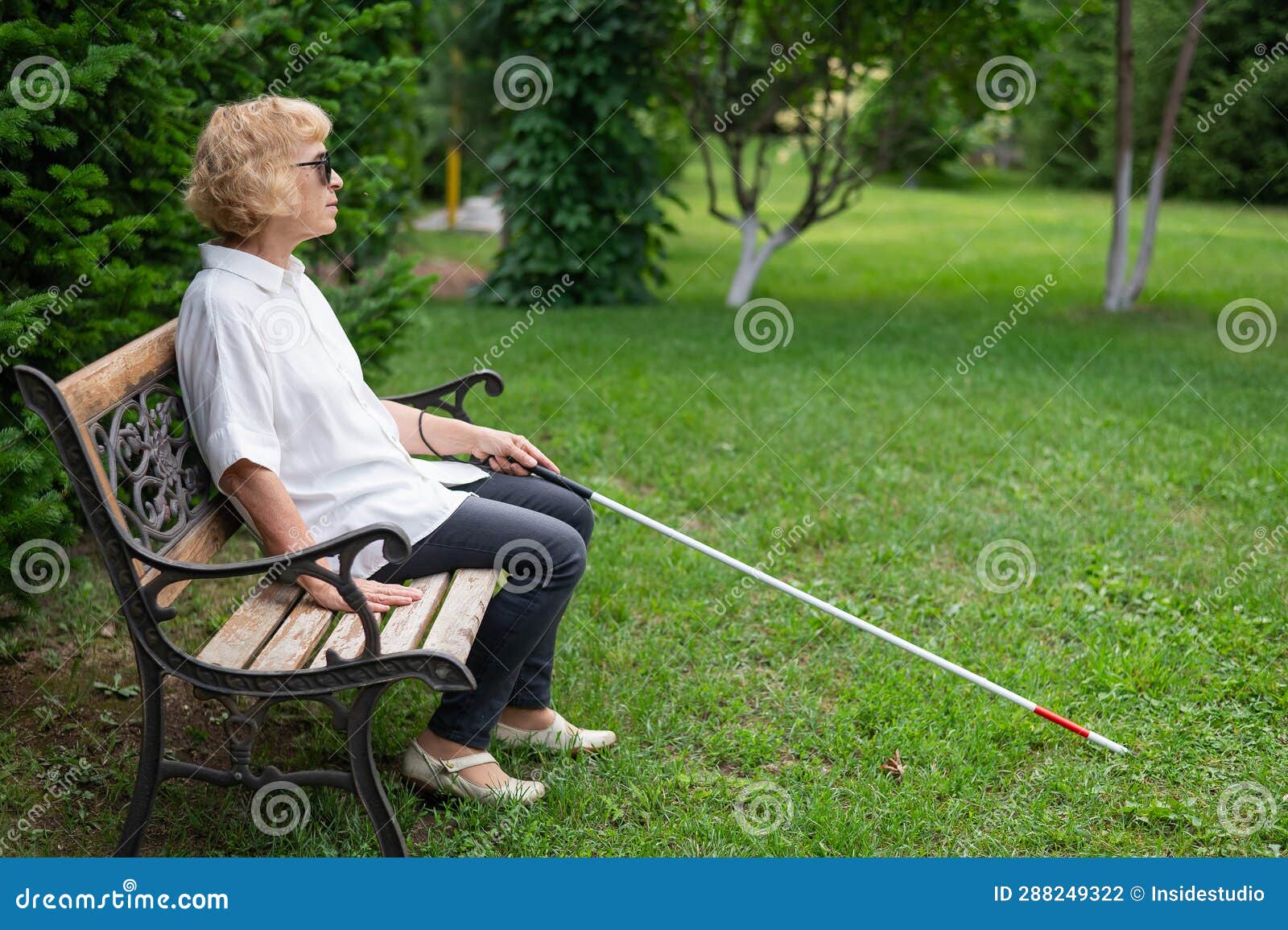 An Elderly Blind Woman Sits on a Bench in the Park. Stock Photo Image