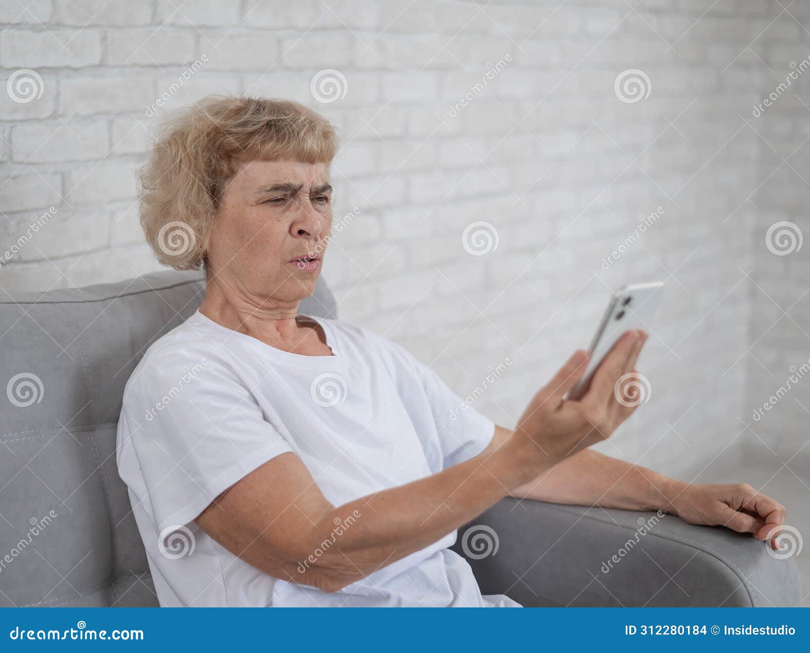 an elderly caucasian woman suffers from farsightedness and tries to read a message on a smartphone with her arm
