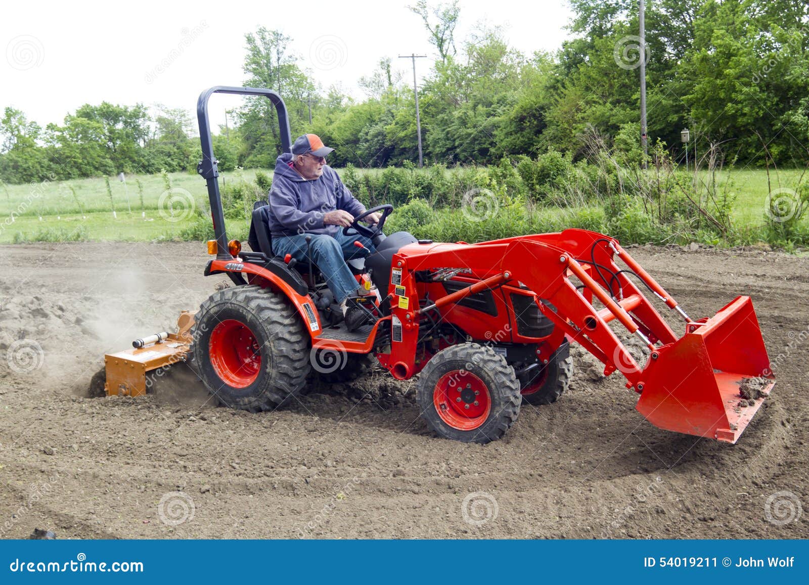 Elderly Farmer Tilling His Garden With A Compact 4x4 Tractor Stock