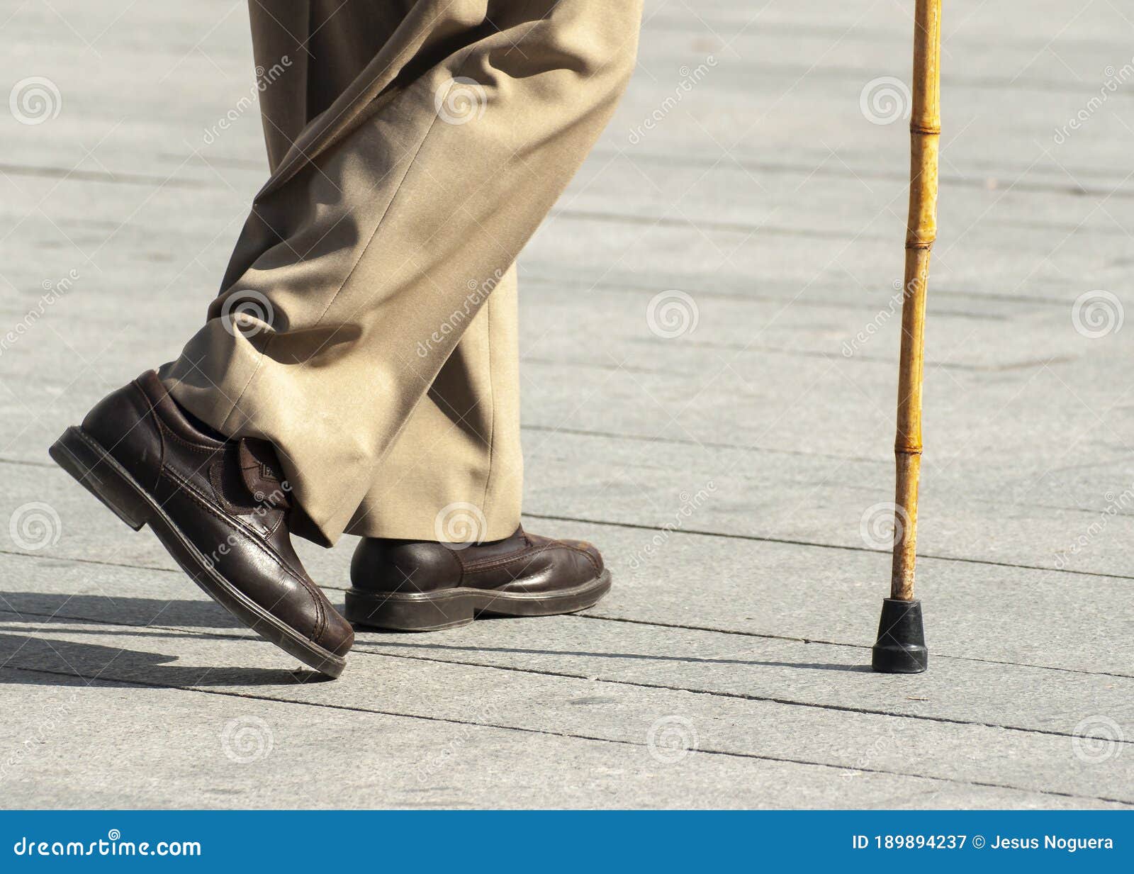 Elderly Person Walking with the Help of a Stick with a Rubber Tip Stock