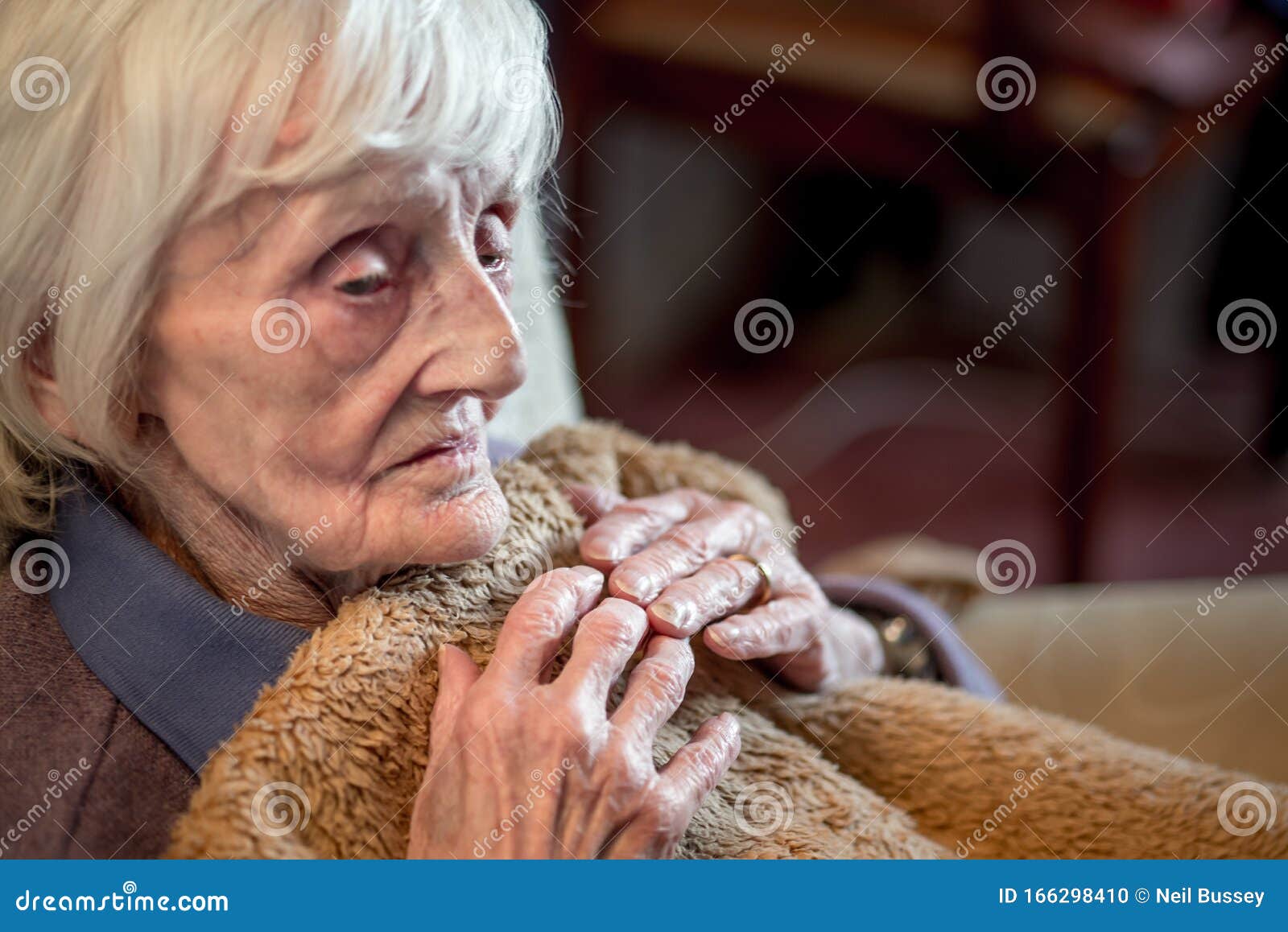 an elderly woman feeling cold at her home during the winter months
