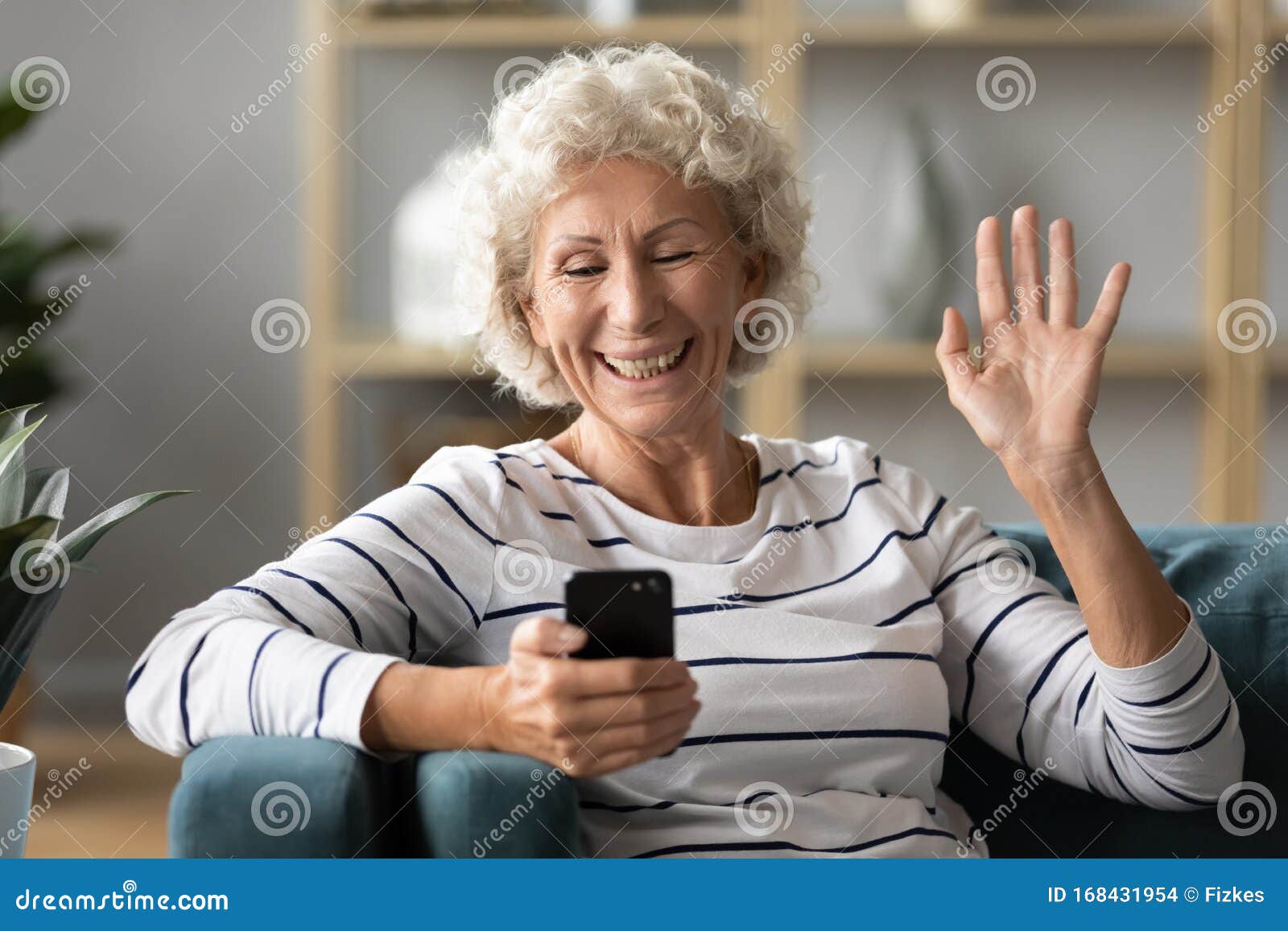 elderly woman holding smartphone wave hand having videocall