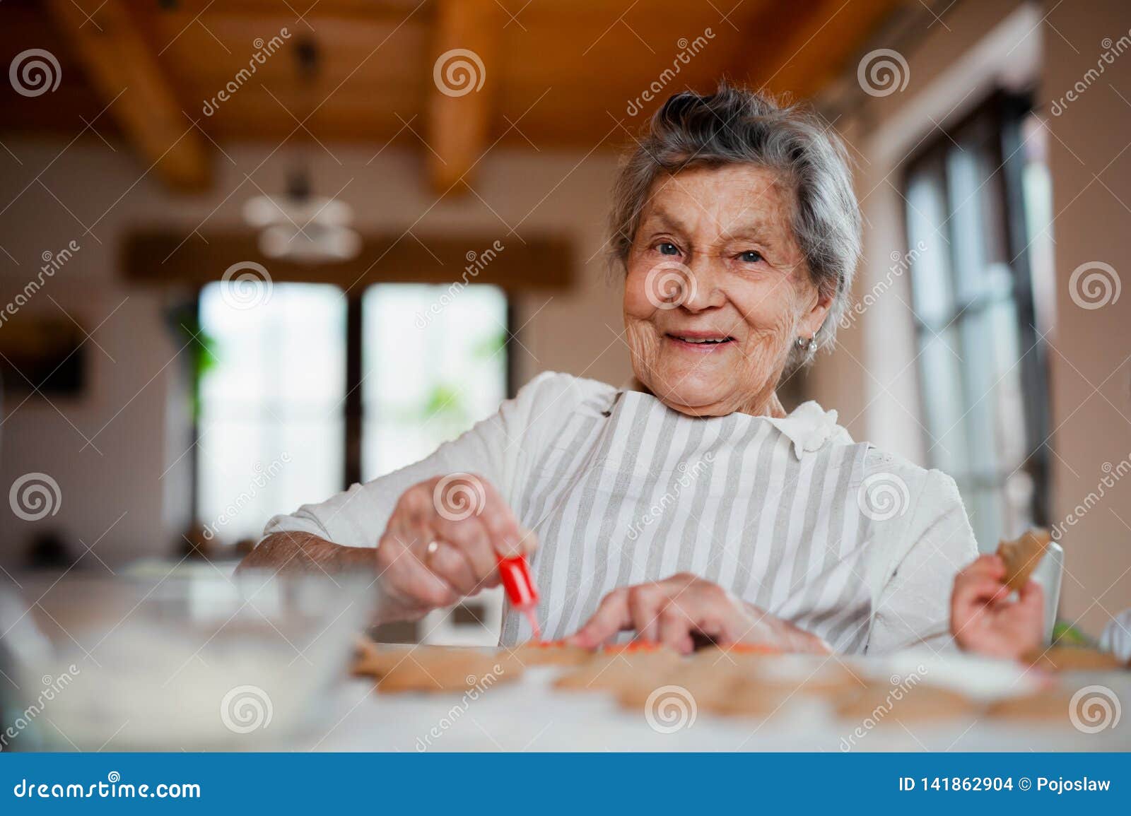 Elderly Woman Making and Decorating Cakes in a Kitchen at Home. Copy Space Stock Photo Image