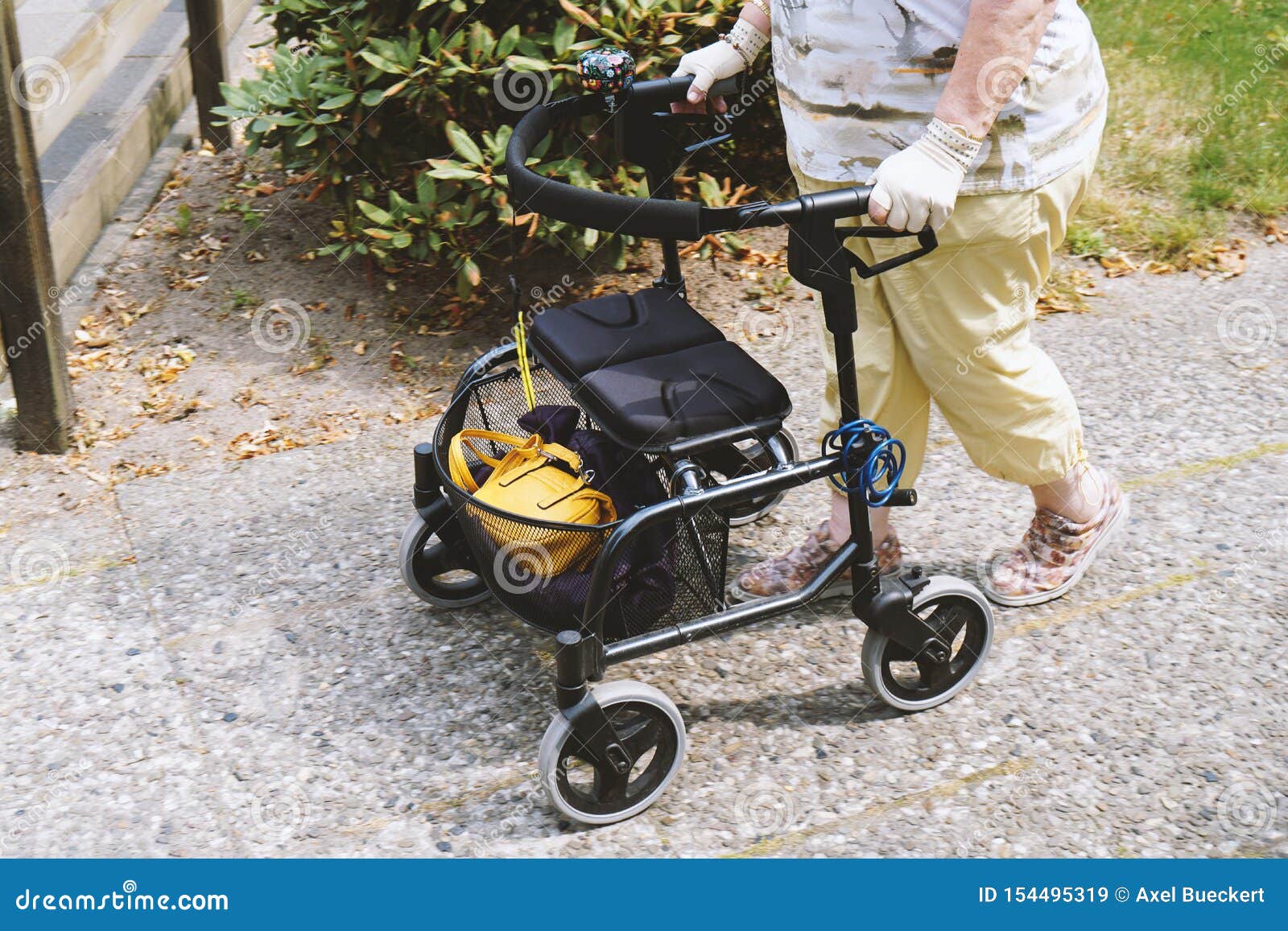 elderly woman walking outside with rollator or wheeled walker