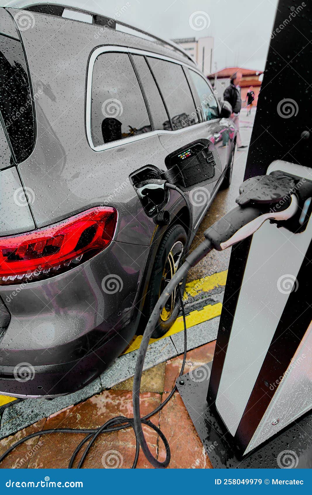 Electric Car on a Rainy Day Connected To Charging Cable Stock Image